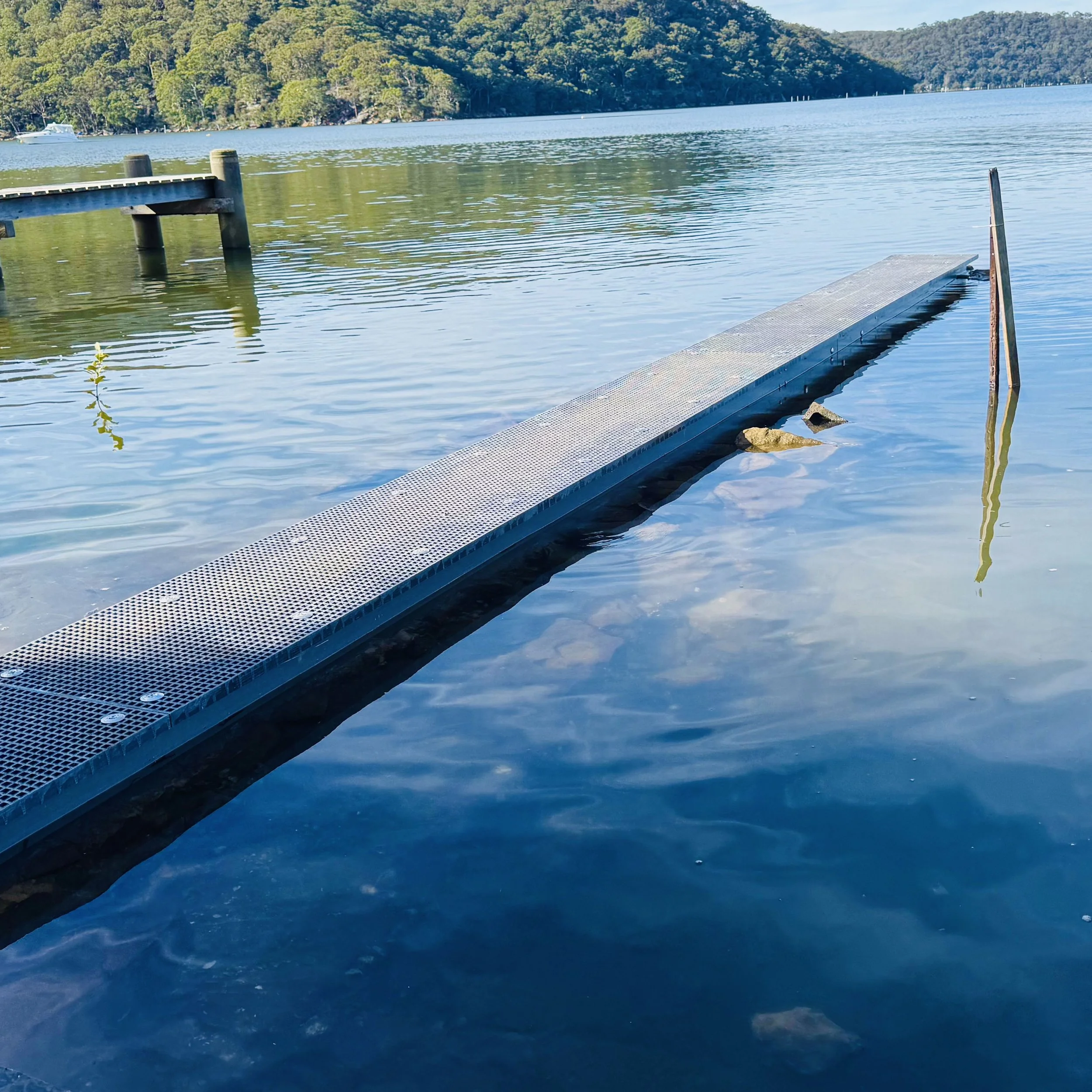 Lakeside FRP dock extending toward calm water and mountain backdrop designed by Platinum Decks to highlight serene, nature‑connected outdoor living