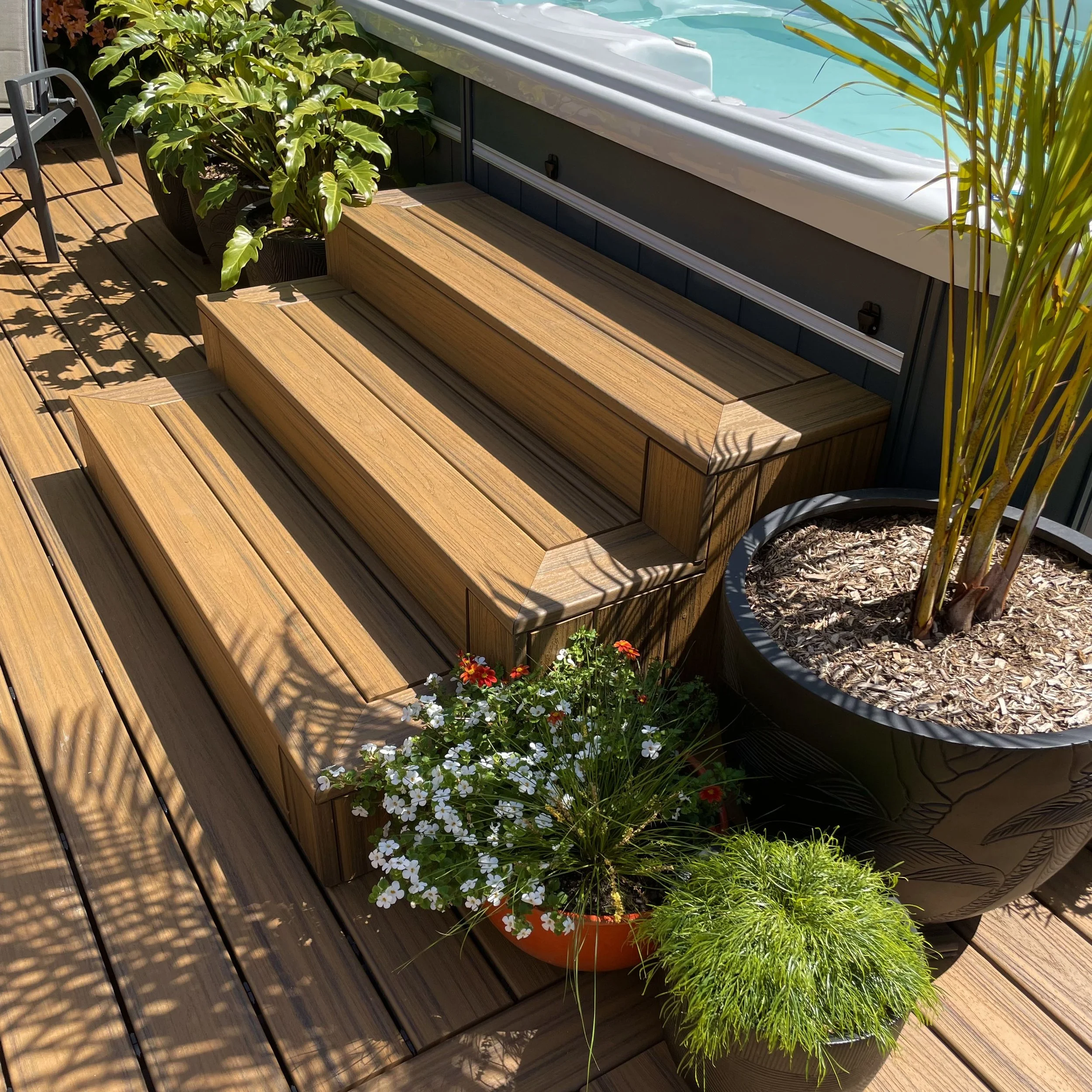 Custom poolside deck with steps and outdoor seating upgraded by Platinum Decks to support high‑traffic entertaining and withstand coastal humidity