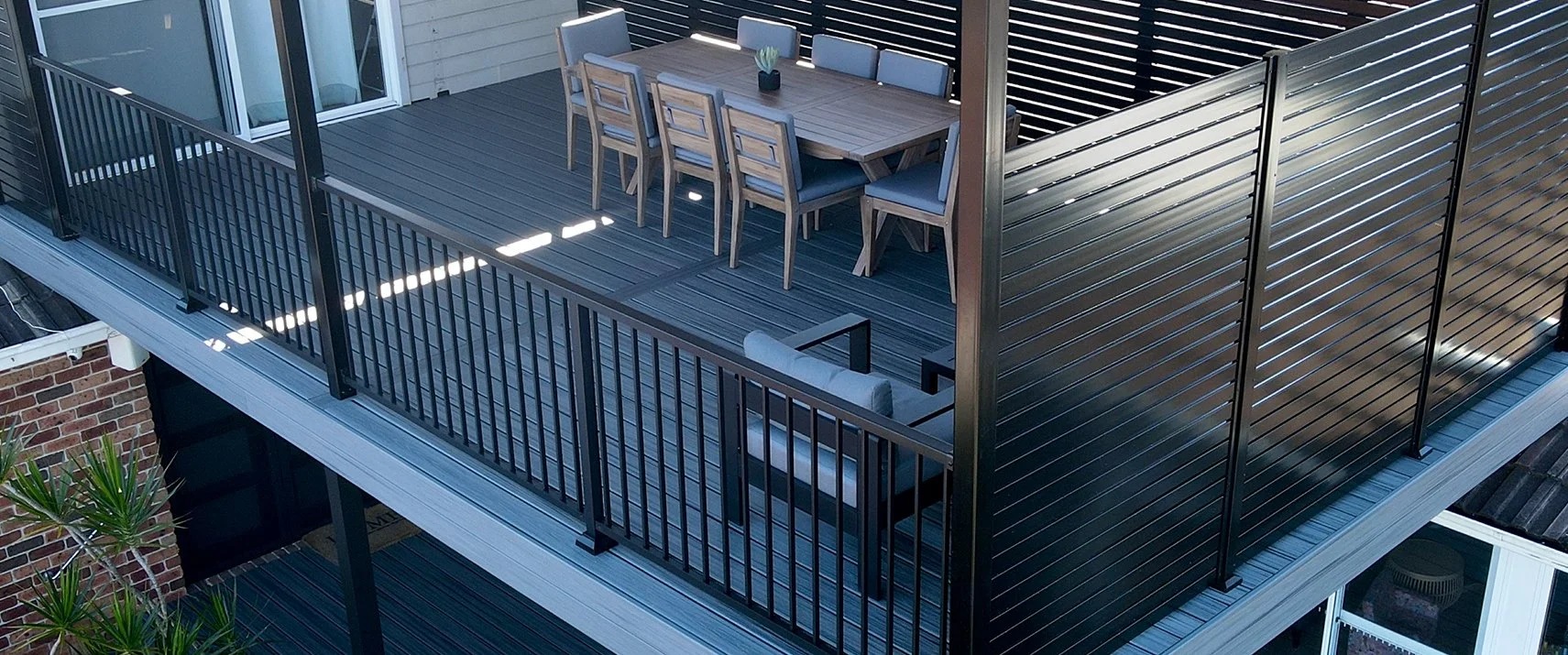 Modern composite deck with sleek furniture and metal railings engineered for long‑term performance in coastal climates, completed by Platinum Decks to elevate everyday outdoor life