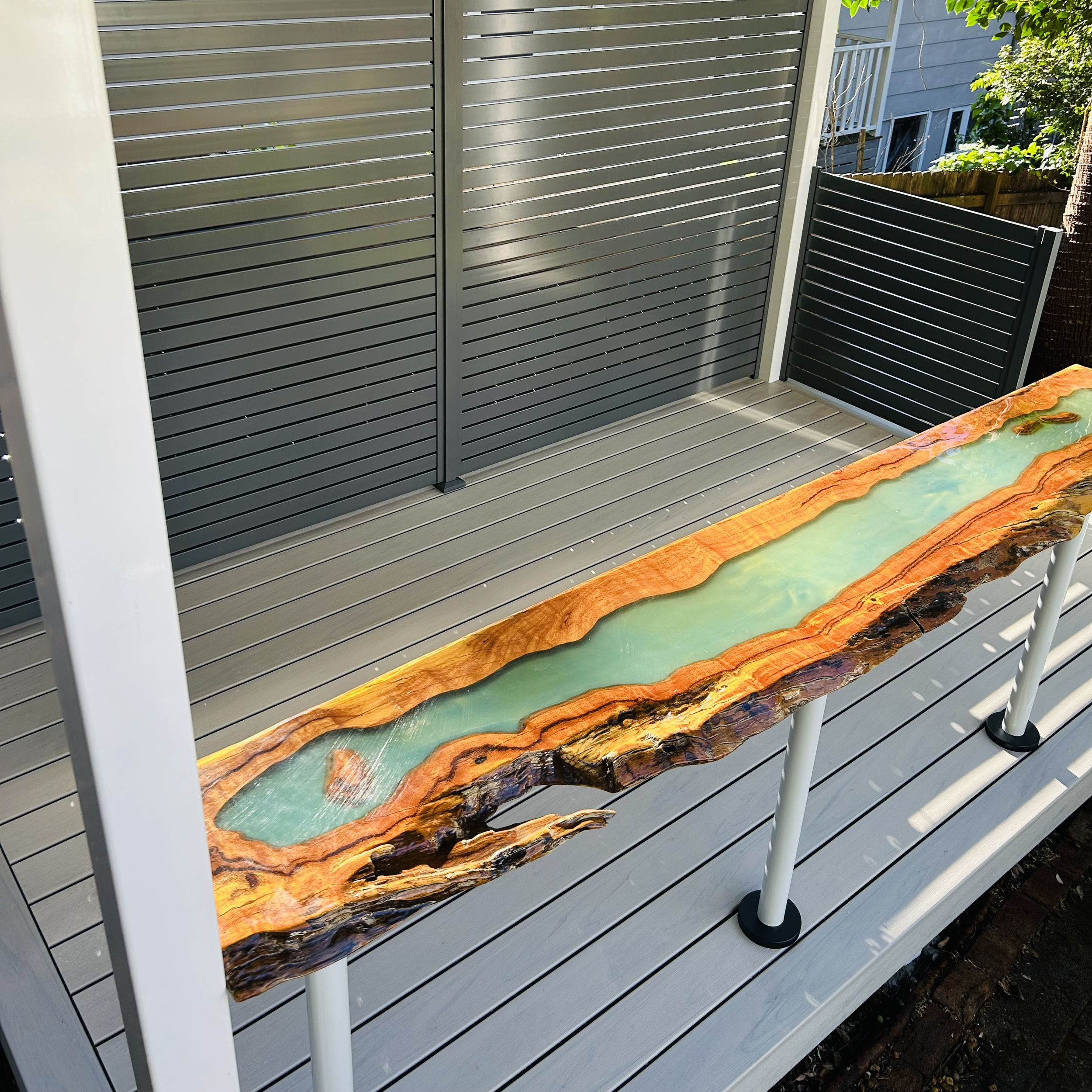 Composite deck with privacy screen and live edge timber resin bar by Platinum Decks & Patios for entertaining gatherings