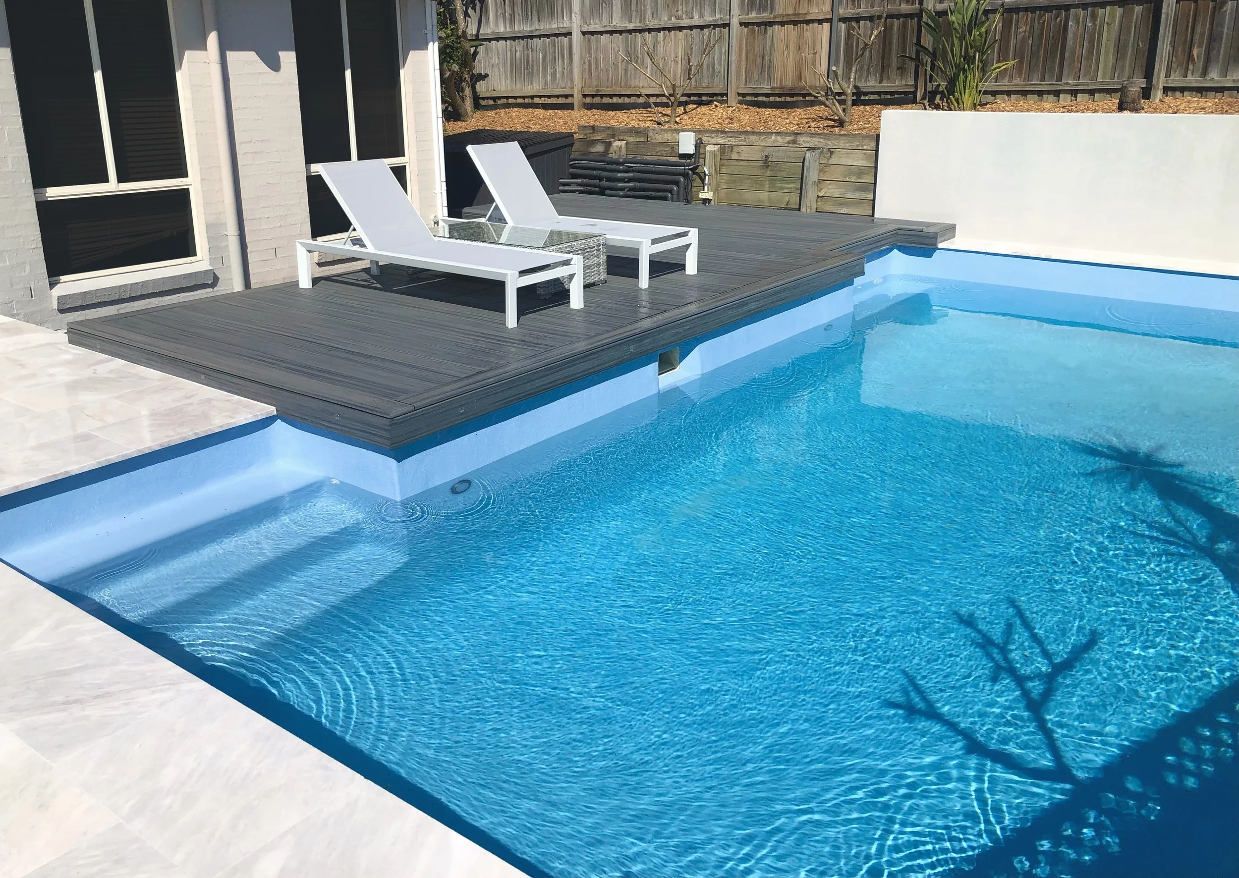 Dark Trex composite sun deck platform built to complement the pool surround. Built by Platinum Decks on the Central Coast.