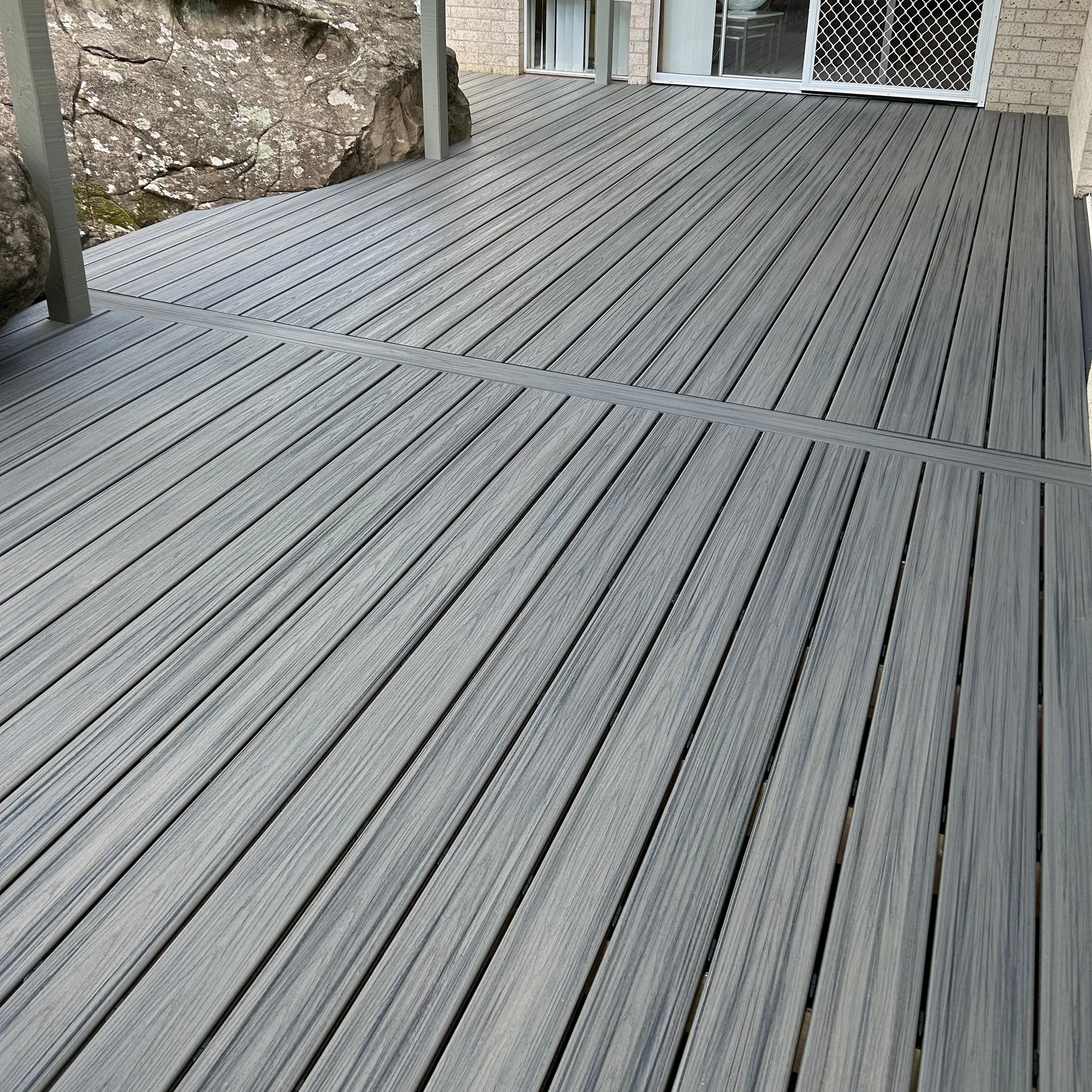 A new composite deck with grey boards running the length of the back of the Central Coast house. Built and installed by Platinum Decks.