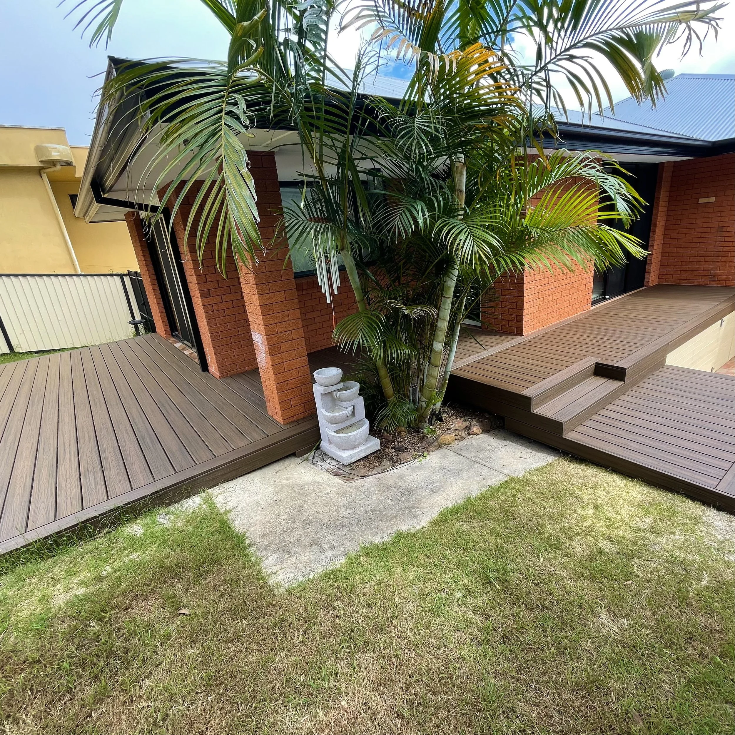 Backyard deck framed by brick exterior and garden plants crafted by Platinum Decks to deliver a refined, nature‑connected outdoor living 