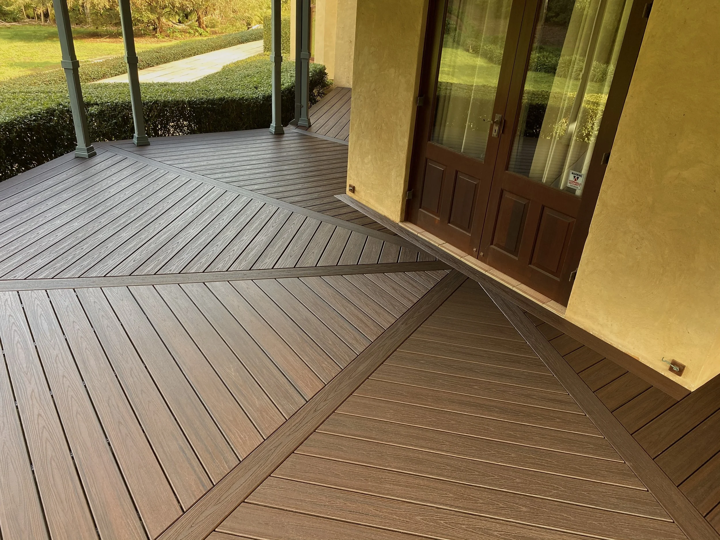 Warm‑tone Trex deck boards in Lava Rock styled beside garden greenery crafted by Platinum Decks to create a luxury, nature‑connected outdoor space