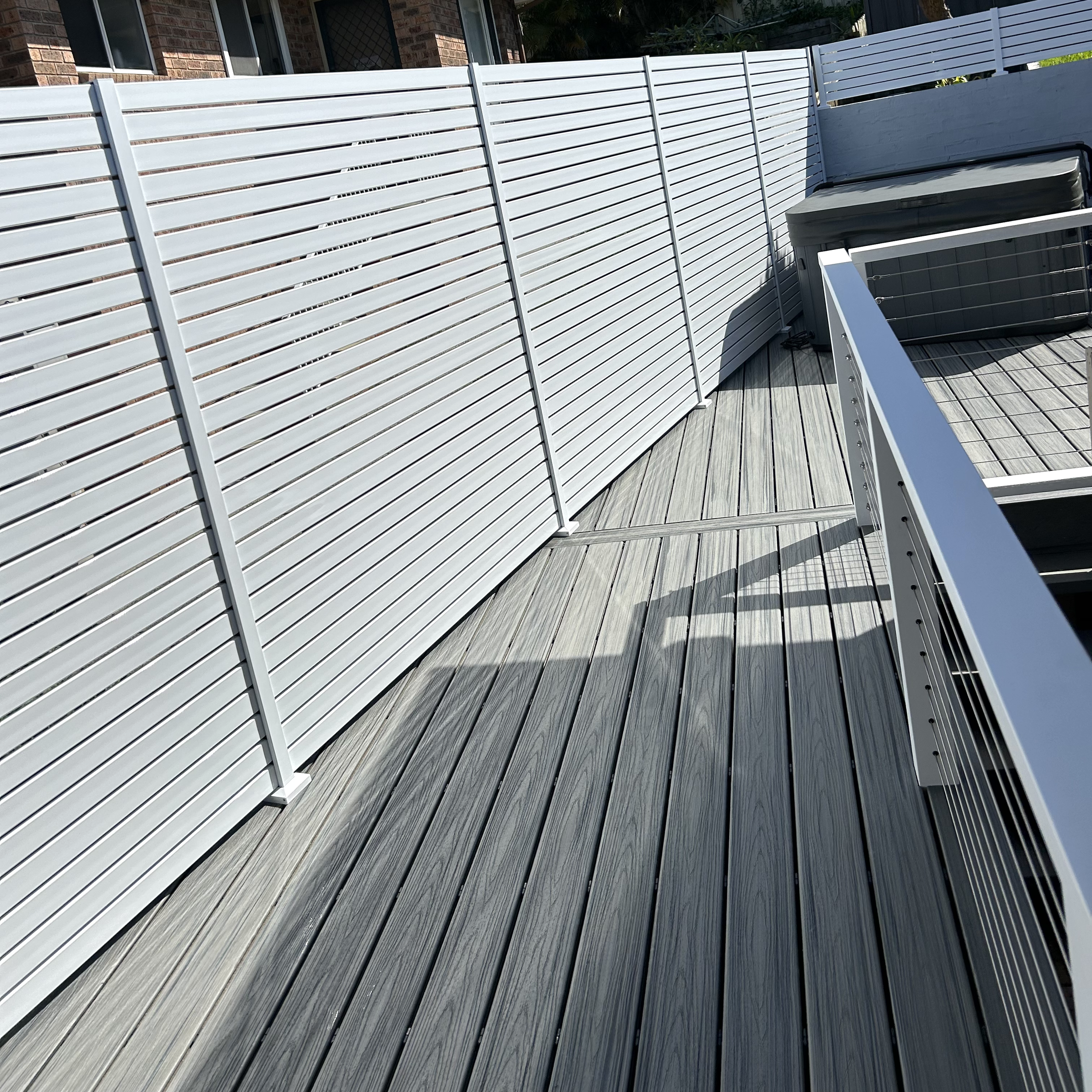 Premium white privacy screen lining a modern deck walkway completed by Platinum Decks to deliver a clean, resort‑style finish suited to Central Coast living