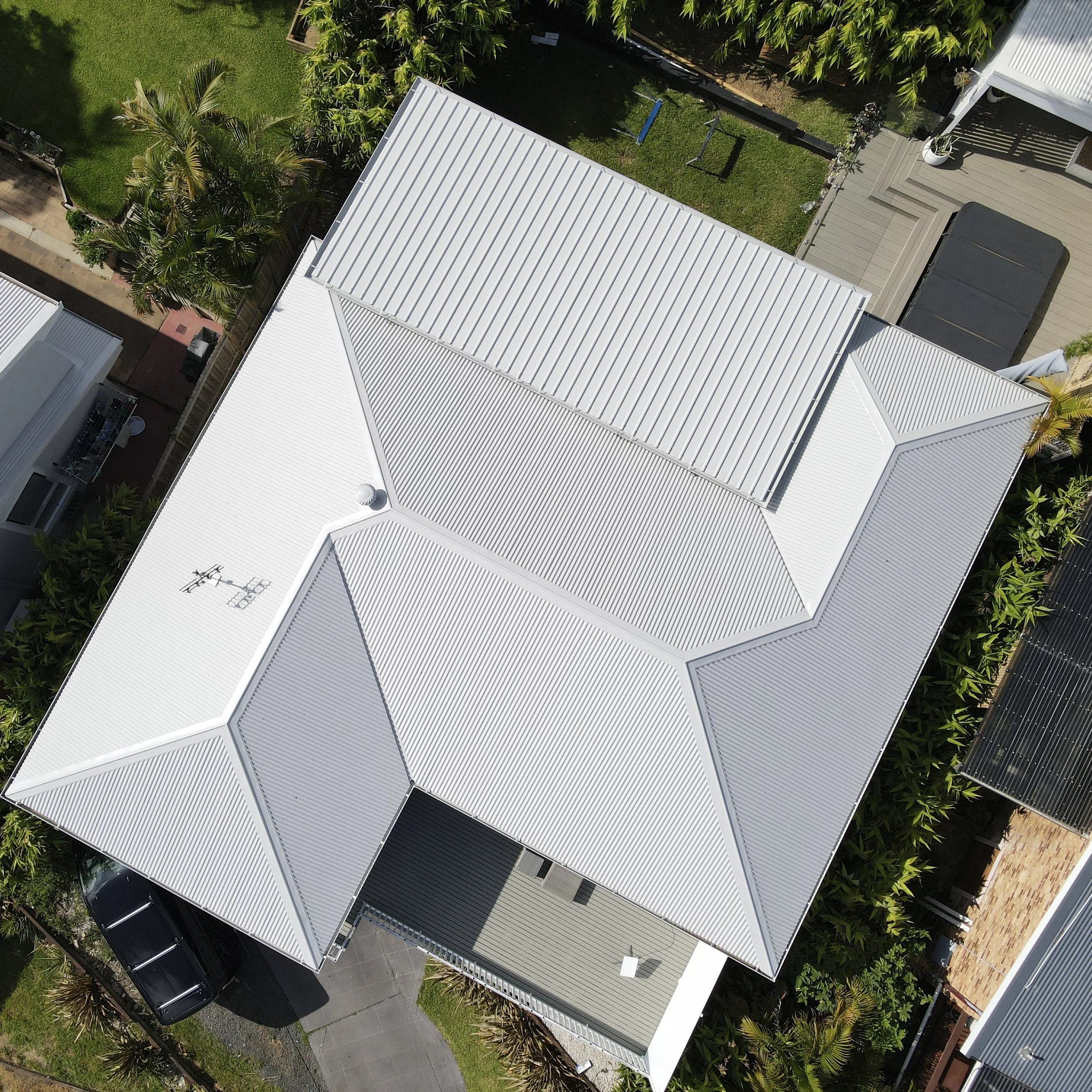 Modern white home with metal roof surrounded by greenery styled by Platinum Decks to showcase clean architectural lines and premium outdoor flow