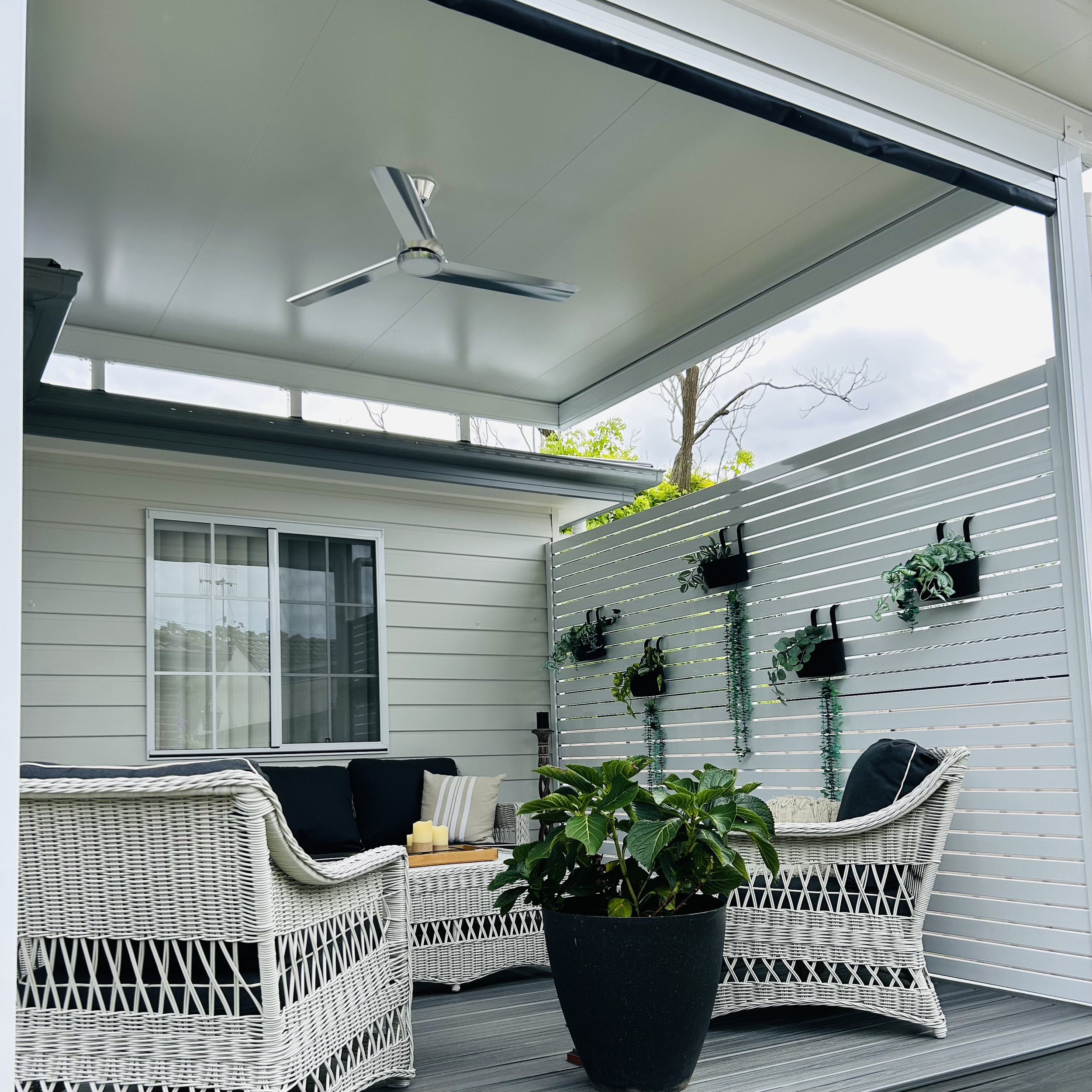 Covered composite deck with pergola roof, ceiling fan and slatted privacy screen, styled as a relaxed coastal outdoor living space built and designed by Platinum Deck on the Central Coast