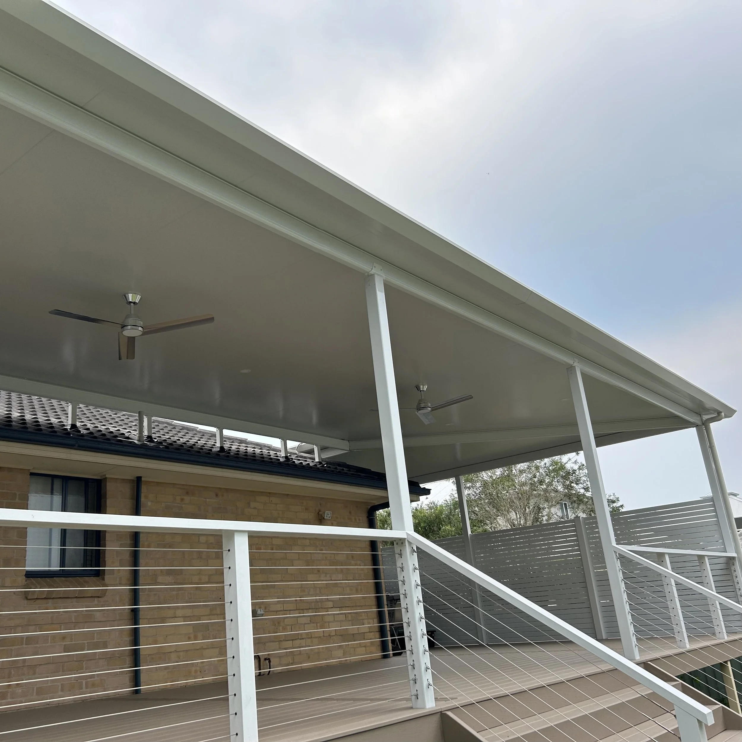 High‑end composite patio with black railings and overhead cover completed by Platinum Decks to create a premium outdoor living space suited to Central Coast conditions