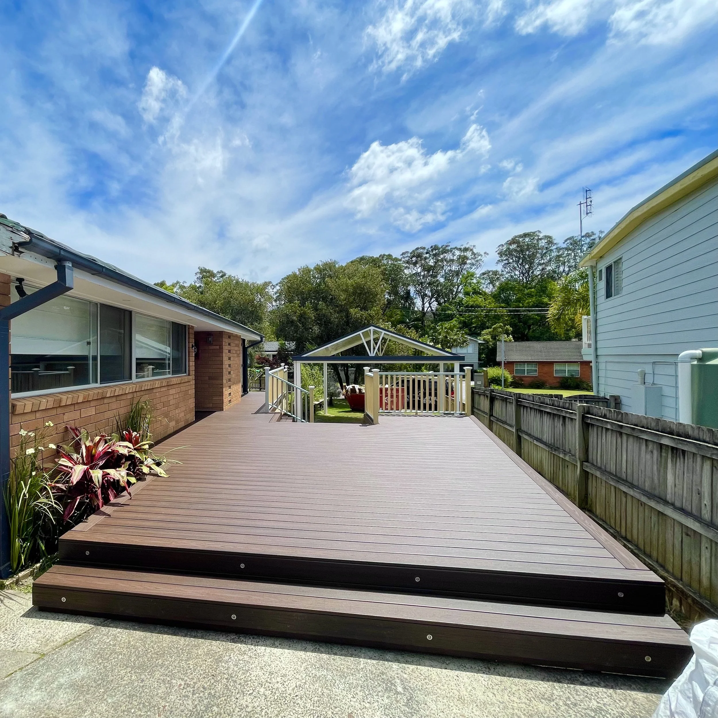 A tiered composite deck in a backyard on the Central Coast built by Platinum Decks. 