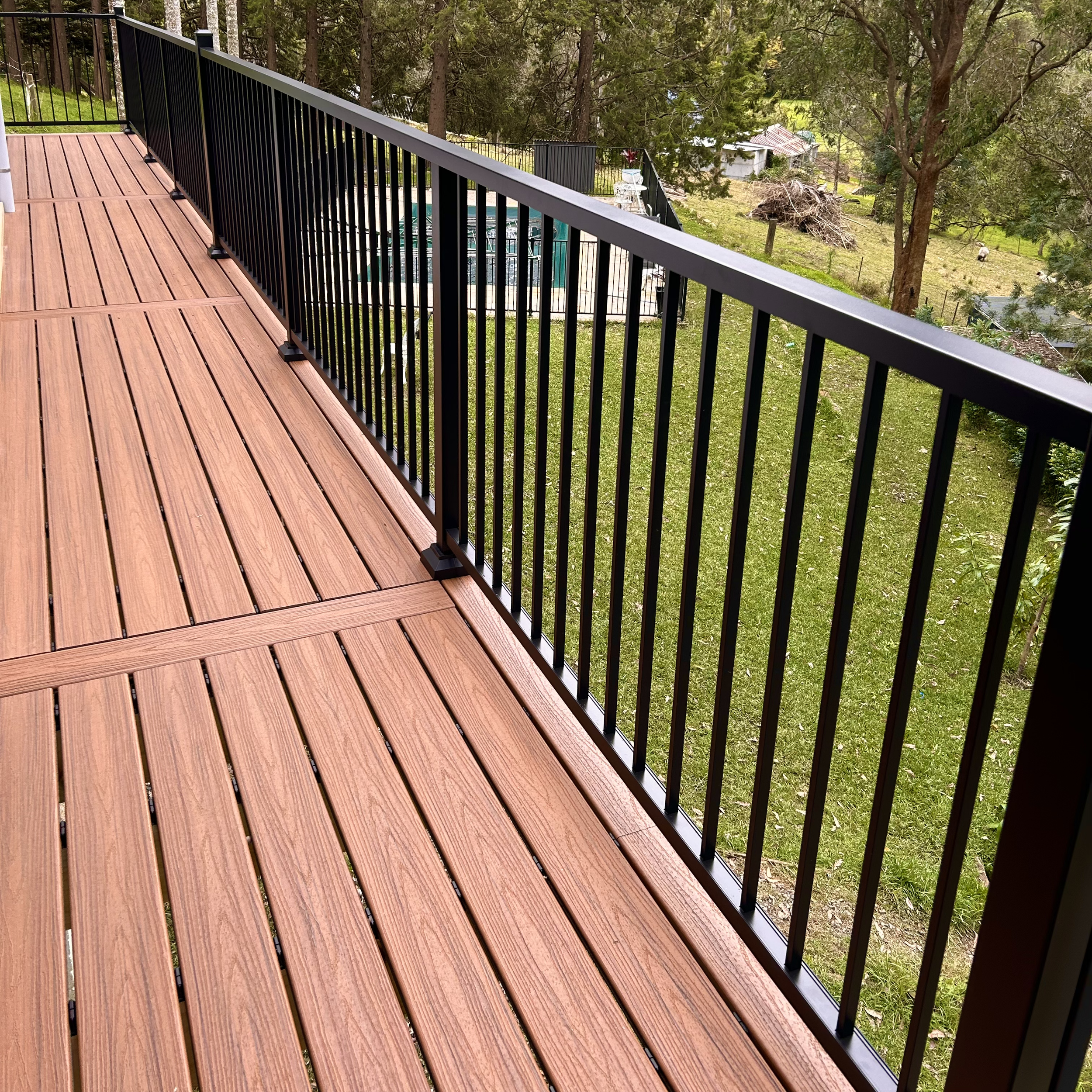 Rich timber‑tone composite deck with luxury black balustrades designed by Platinum Decks to create a sophisticated outdoor entertaining space