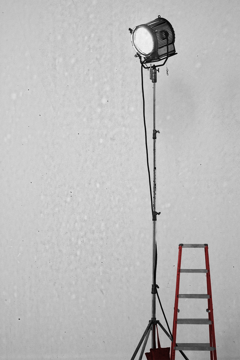 Black and white film production studio light on a stand beside a red ladder — representing the behind the scenes craft of Bay Area filmmaking.