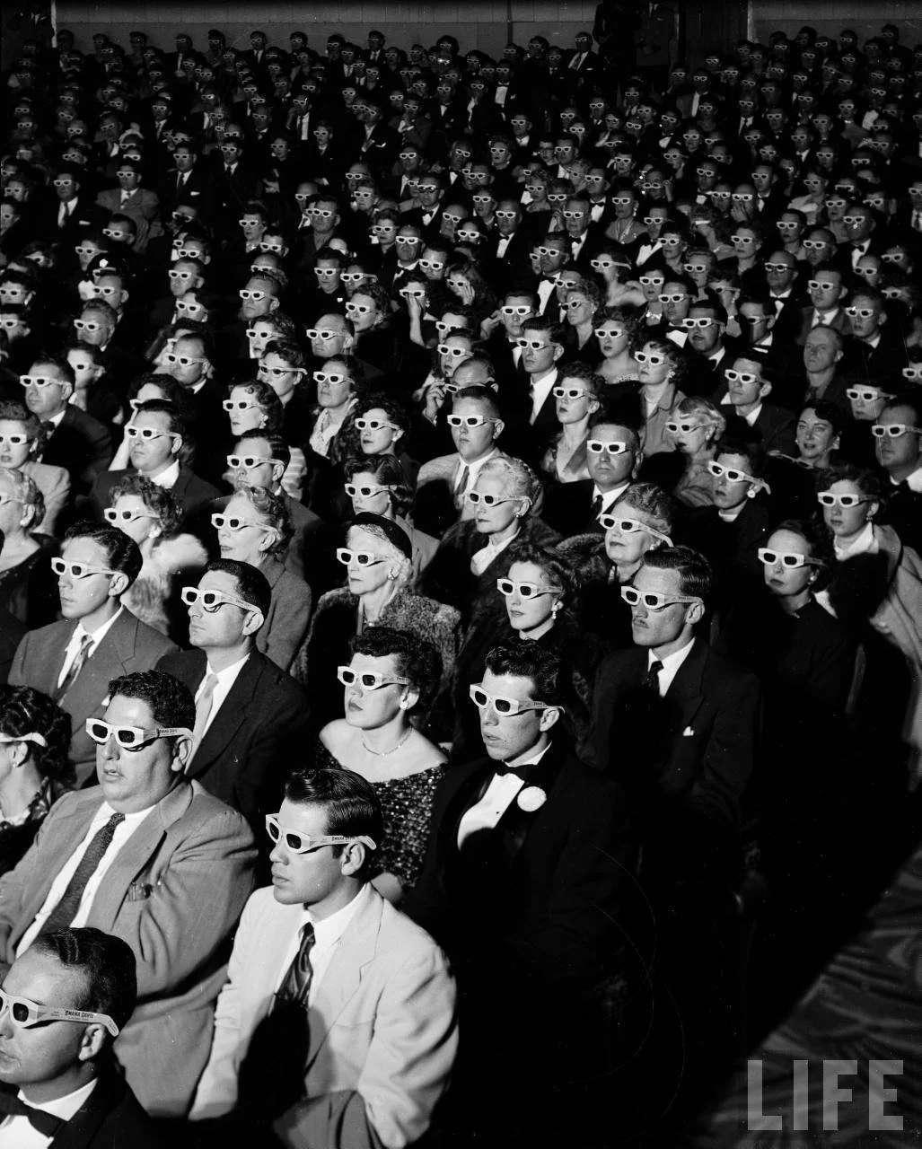 Vintage 1950s black and white photograph of a packed movie theater audience wearing 3D glasses.