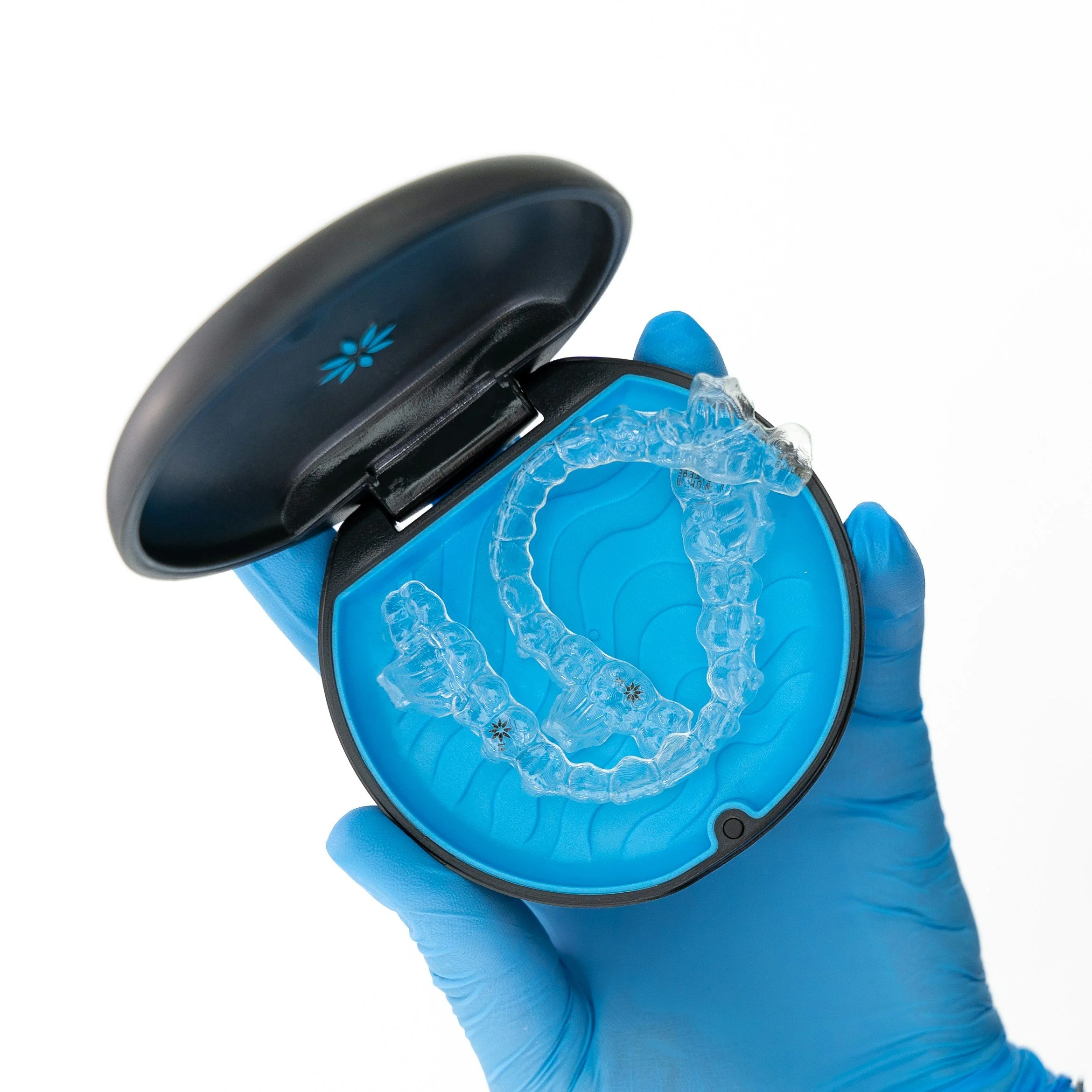 A person wearing blue gloves opening a black case containing ice packs and medical supplies.