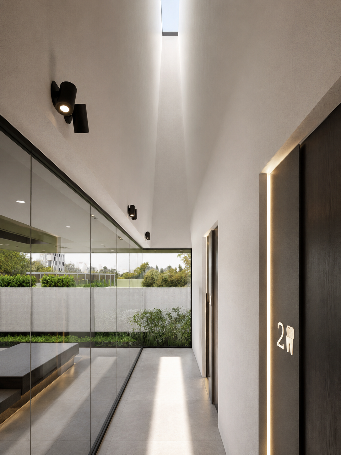 Modern hallway with glass walls, black lighting fixtures, two elevator doors, and a sign indicating women's restroom, with greenery visible outside.