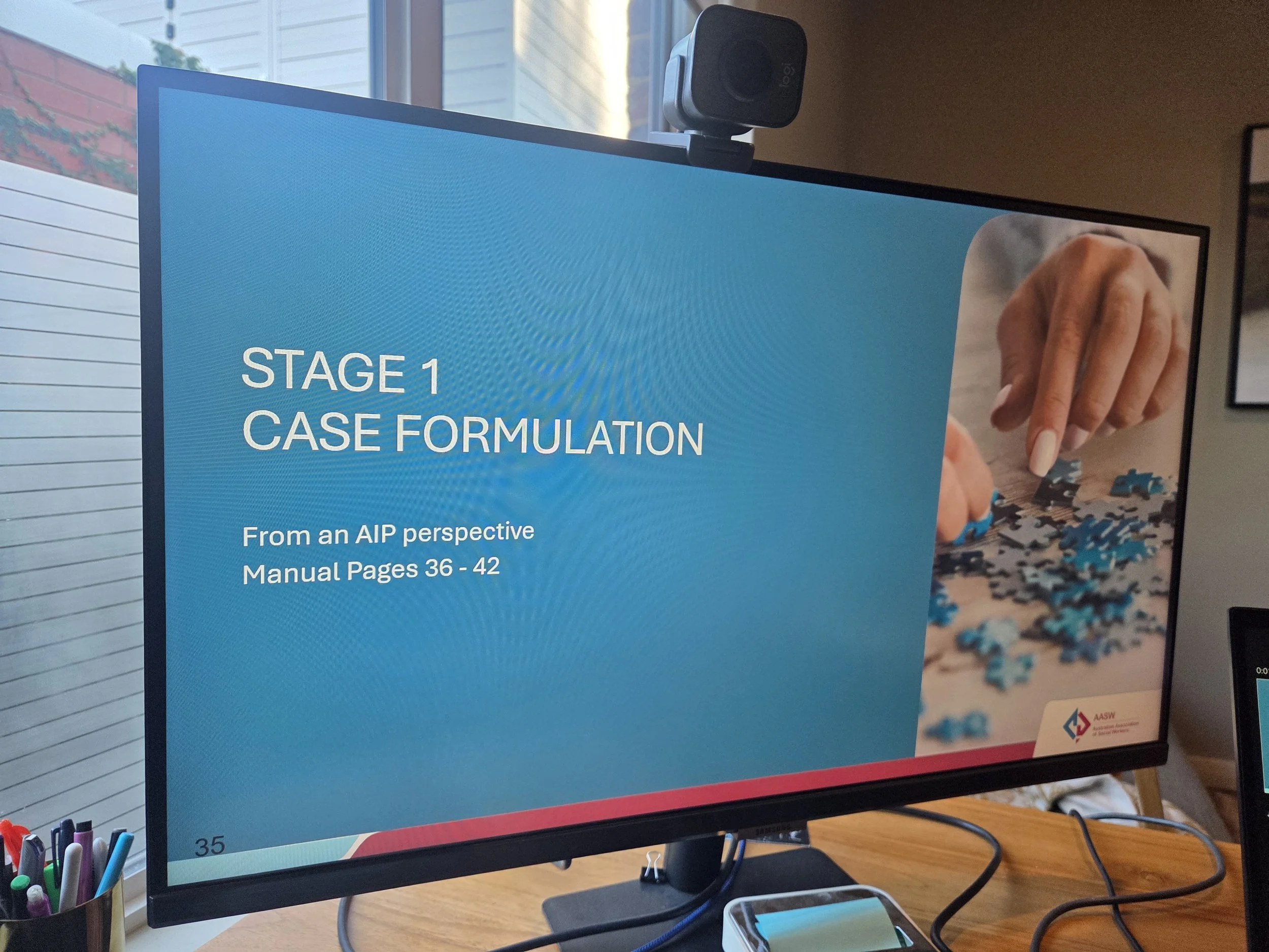 Computer monitor displaying a presentation slide titled 'Stage 1 Case Formulation' with a photo of a person's hand assembling puzzle pieces.
