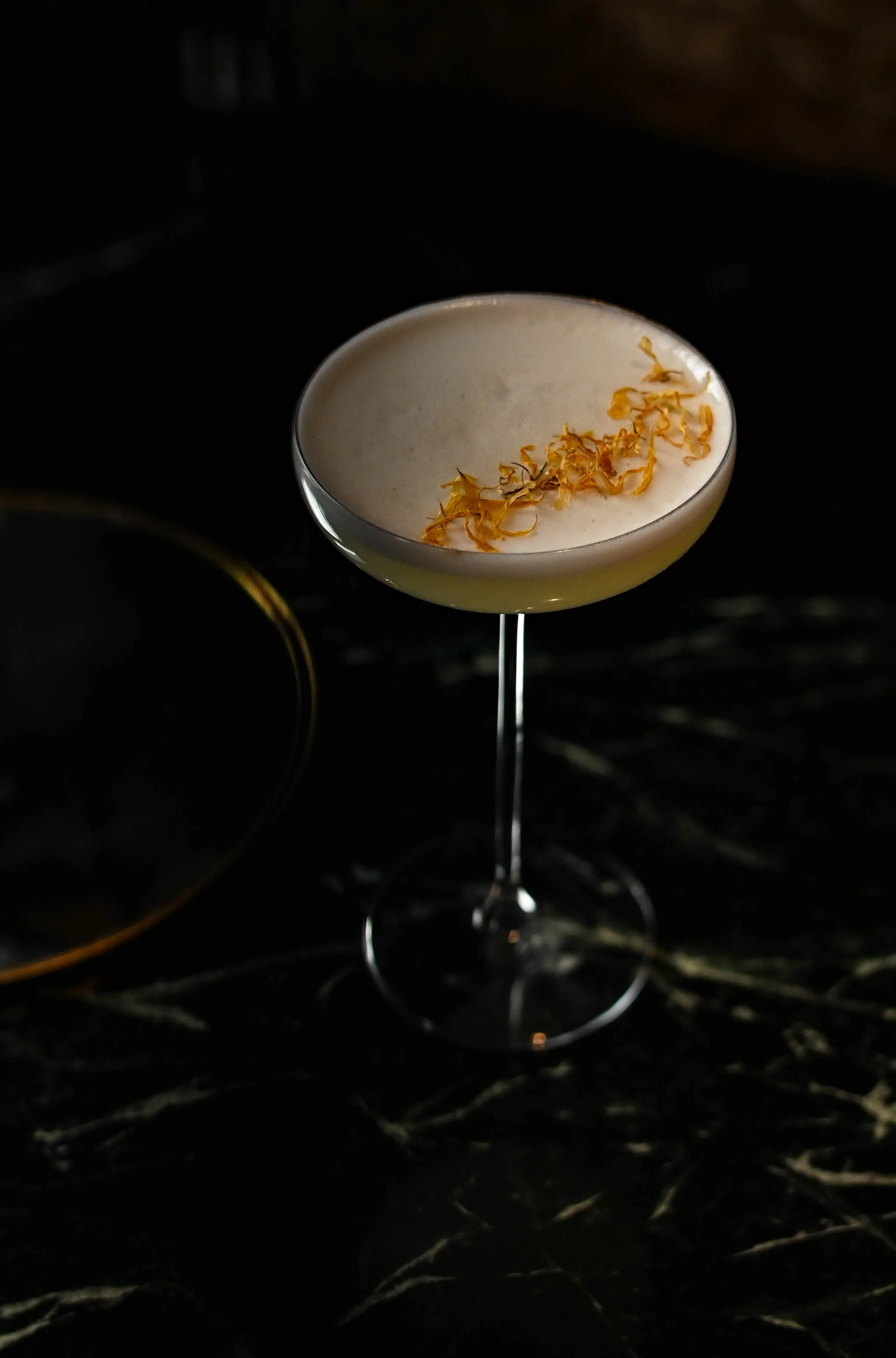 Verre à cocktail sur une surface sombre avec décoration de fleurs sèches.