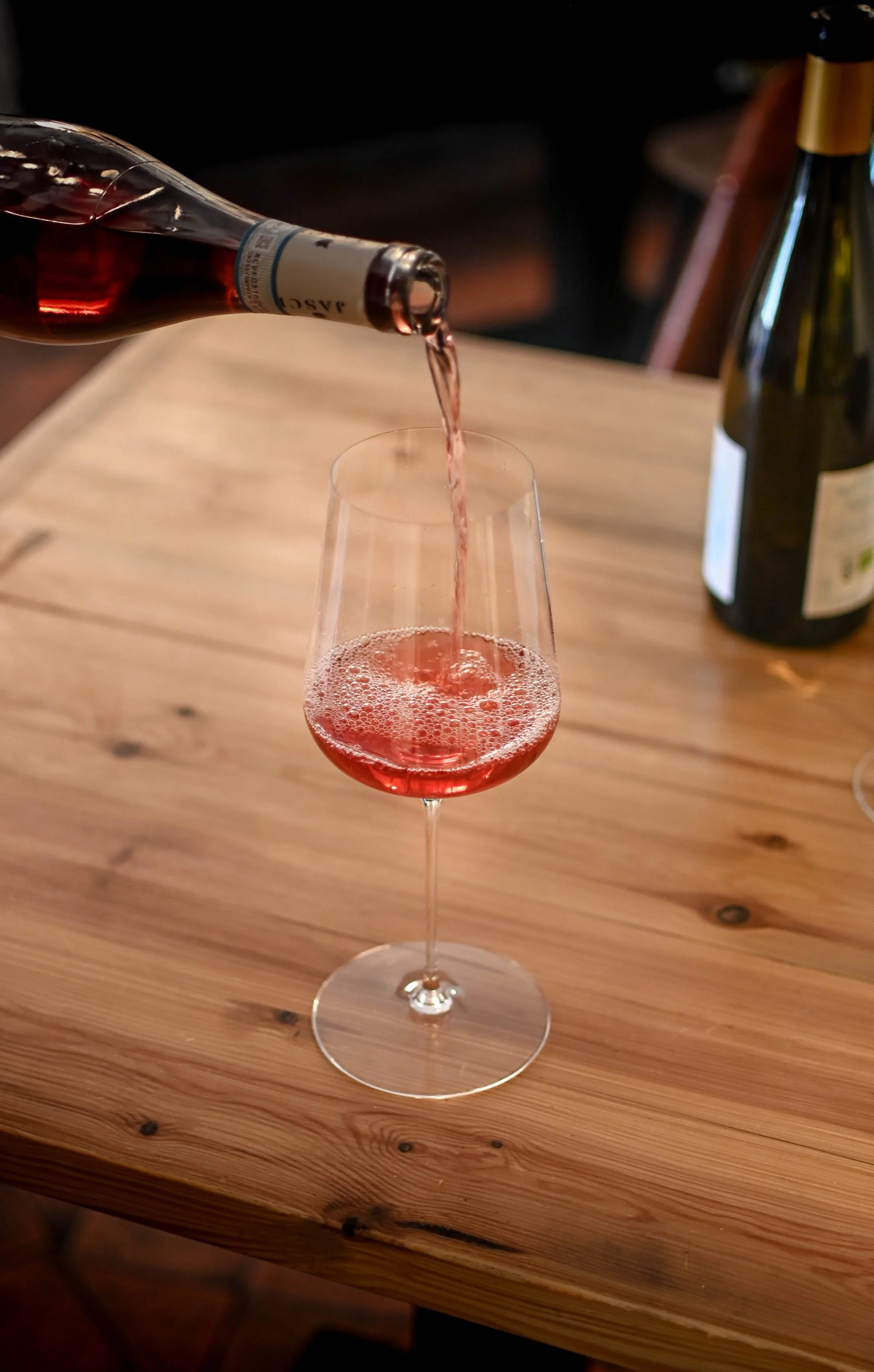 Une bouteille de vin rosé est en train d'être versée dans un verre à vin.
