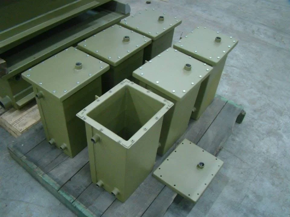 Groene metalen behuizingen met deksels en bevestigingsschroeven. Een van de behuizingen is open, en er ligt een losse deksel op de vloer.