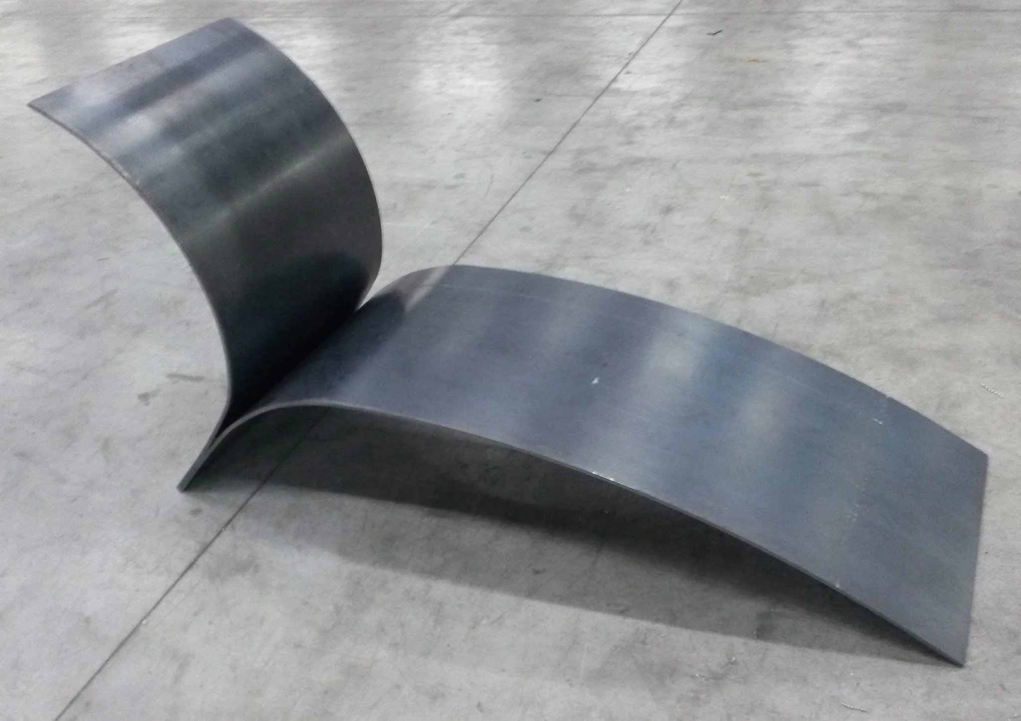 Een moderne bank met een metalen frame en leren zitting, geplaatst op een betonnen vloer.