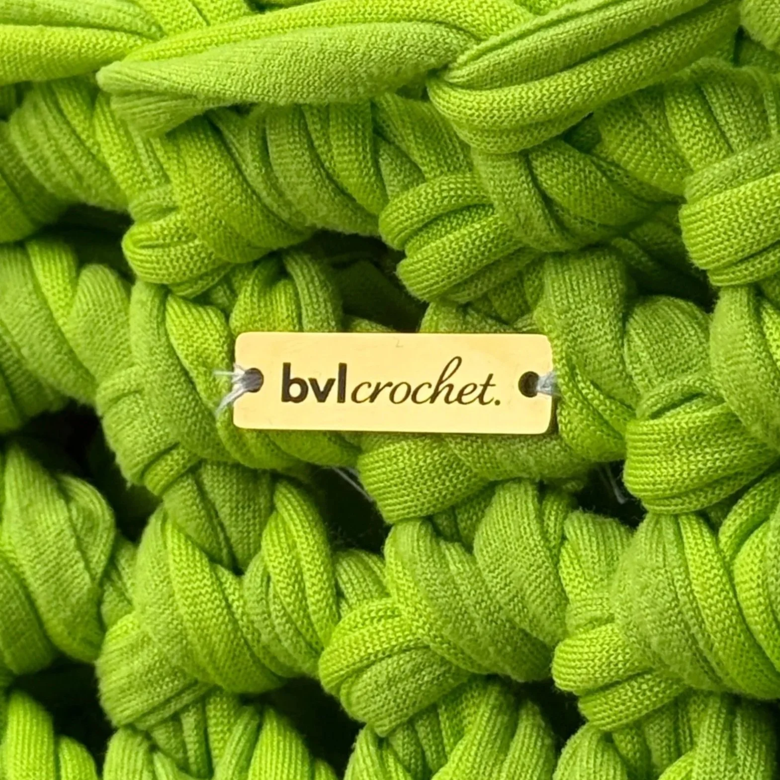 Close-up of neon green woven shoelaces with a small beige label that reads 'bvlcrochet' attached to one of the laces.