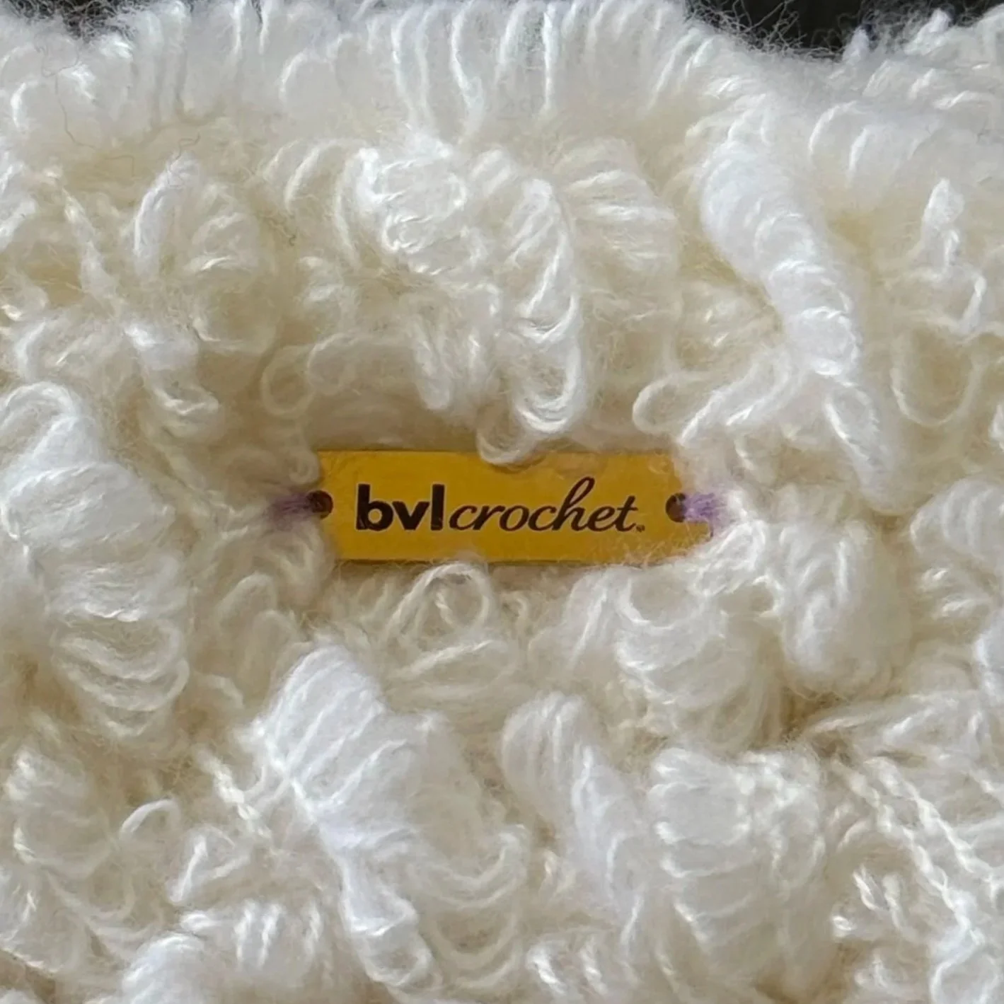 Close-up of a fluffy, cream-colored crochet yarn with a yellow label that reads 'BVL crochet'.