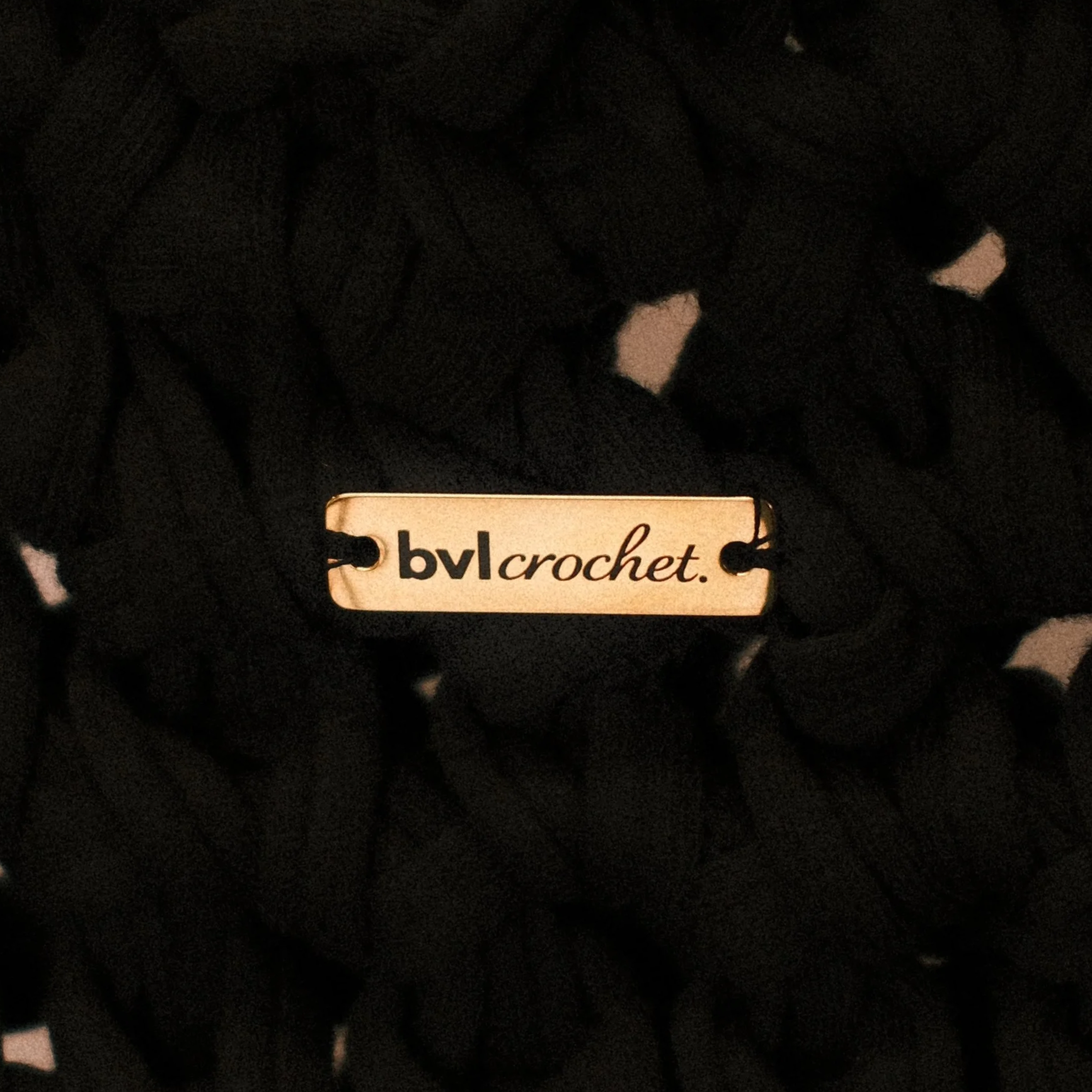 Black yarn on a dark background with a white and black label that says 'bvl crochet.'