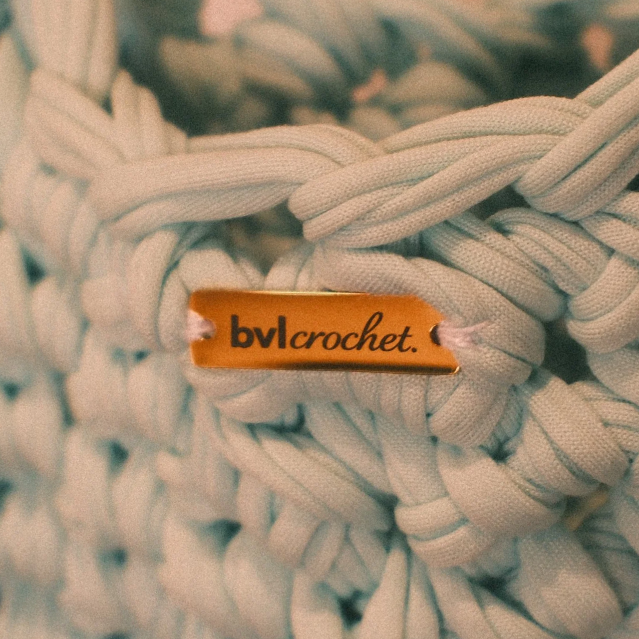 Close-up of white shoelaces with a gold tag reading 'bvlcrochet.' attached to them.