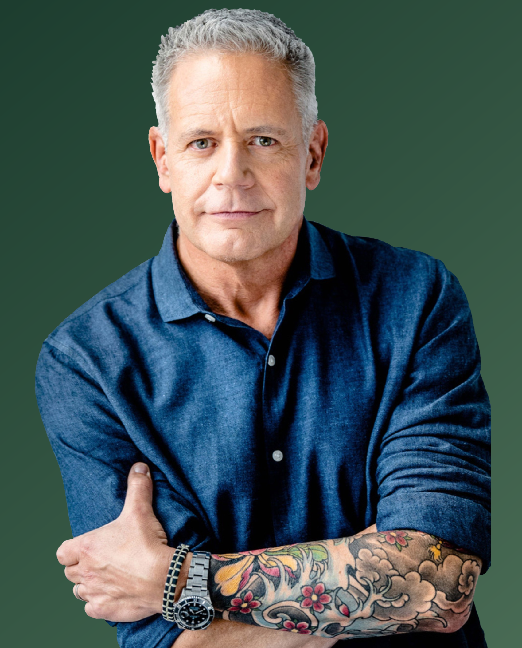 A photo of Michael Bush with tattoos on his arm, wearing a blue linen shirt and a silver watch, standing against a dark green background.