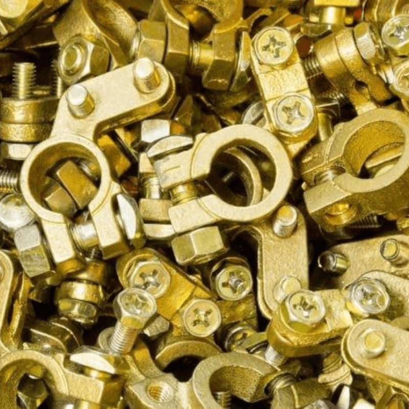 A close-up view of numerous gold-colored mechanical clamps and fasteners, including screws, nuts, washers, and adjustable pipe fittings.