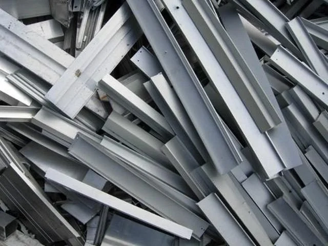 Piles of metallic metal pieces, likely aluminum, stacked haphazardly.