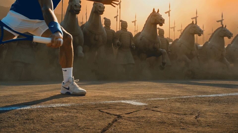 A runner preparing to start a race with ancient warriors and horses statues in the background at sunset.