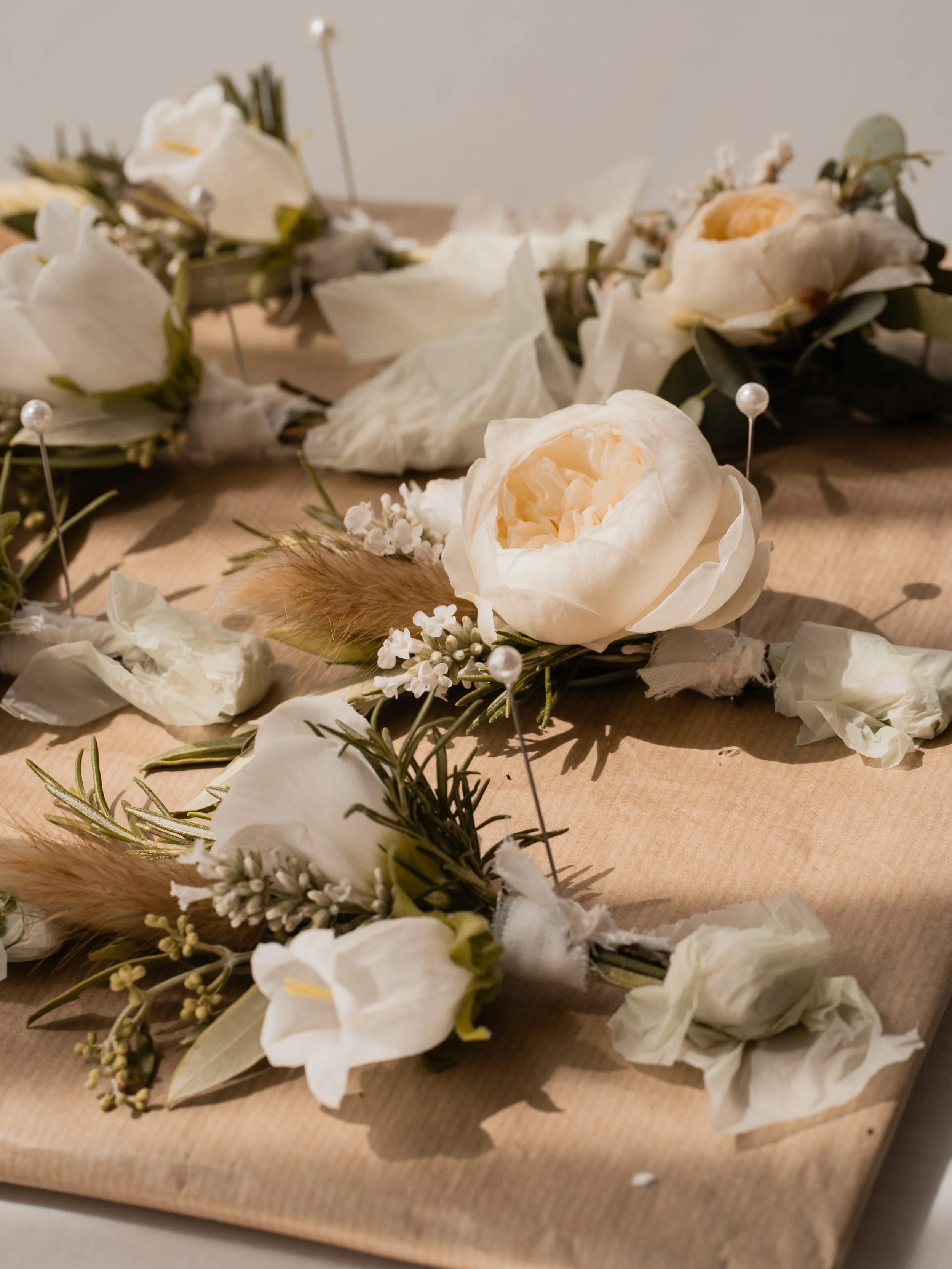 Scattered white flowers, petals, and small decorative pearls on brown paper