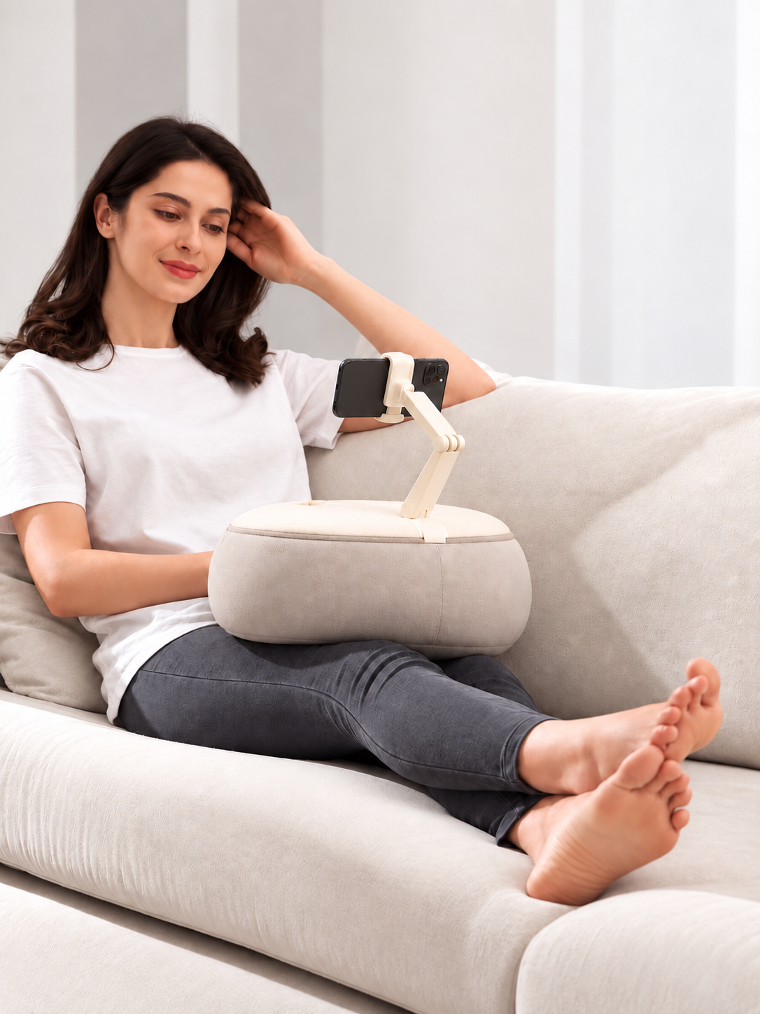Woman relaxing on a sofa with an ALYVI cushioned phone stand positioned for hands-free viewing.