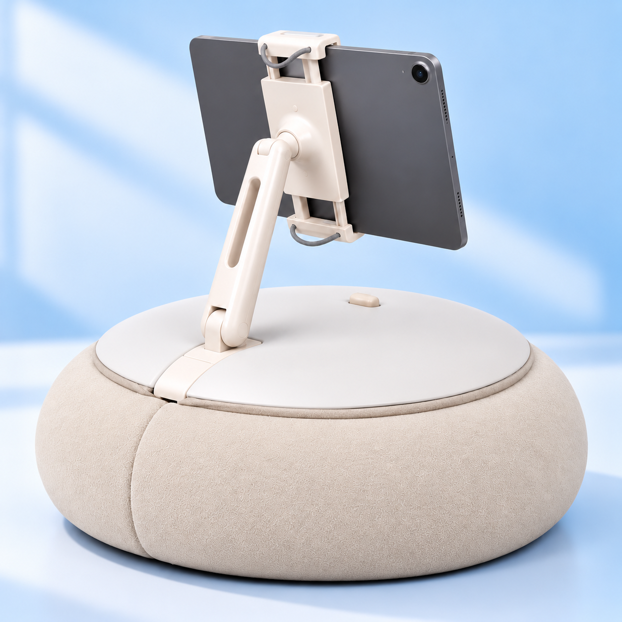 A tablet mounted on a flexible adjustable stand attached to a round, soft, beige cushion base.