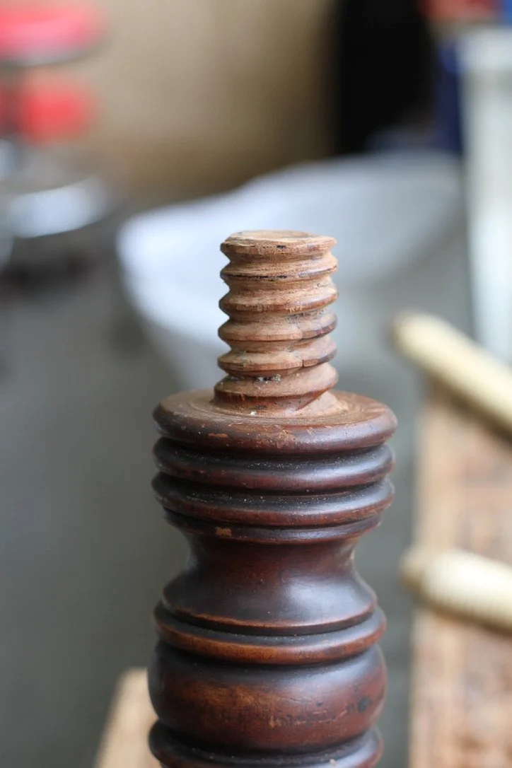 Close-up of a repaired hand cut wooden screw, with blurred background.