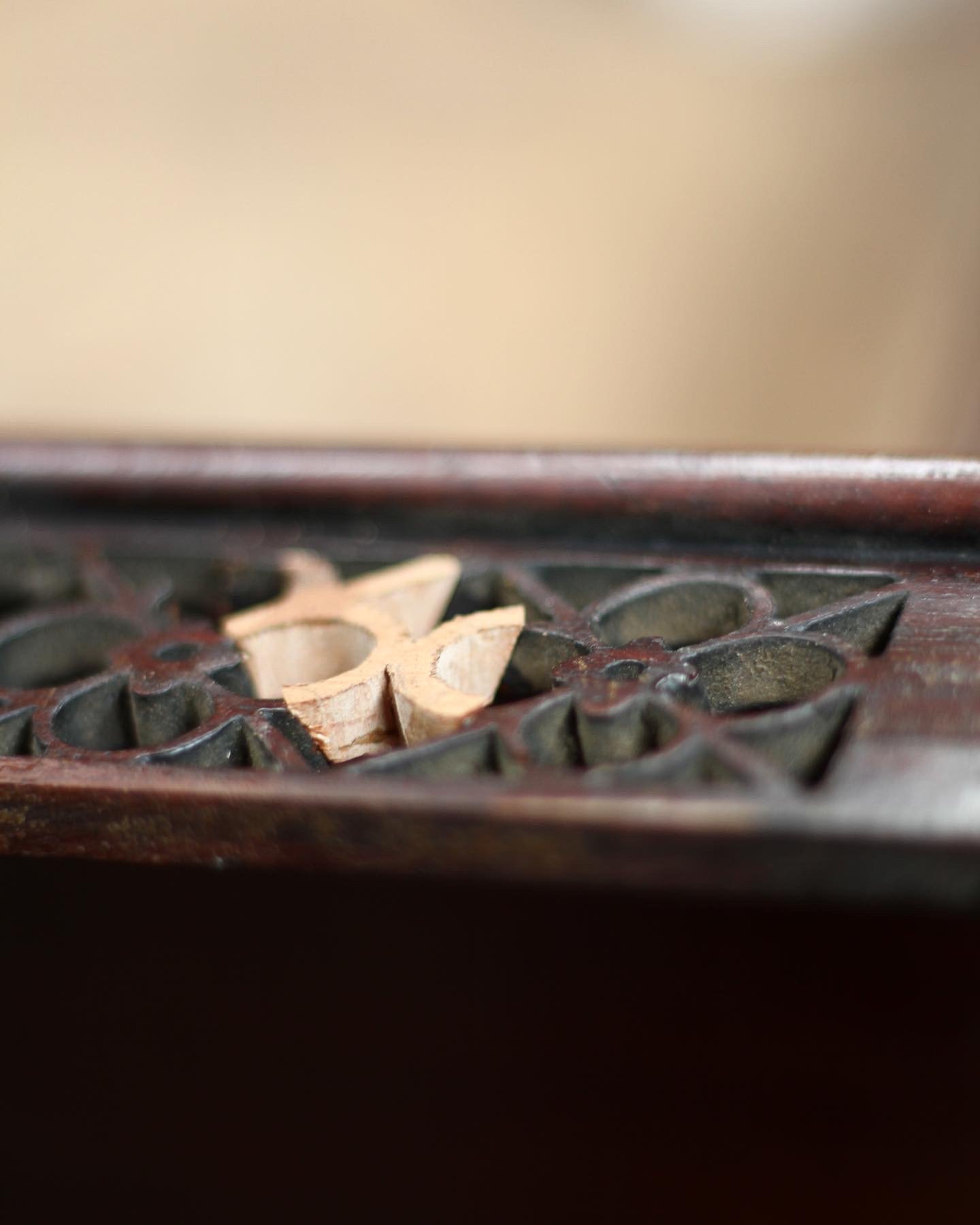 A close-up of decorative fret work vent with a timber patch cut to match the pattern.