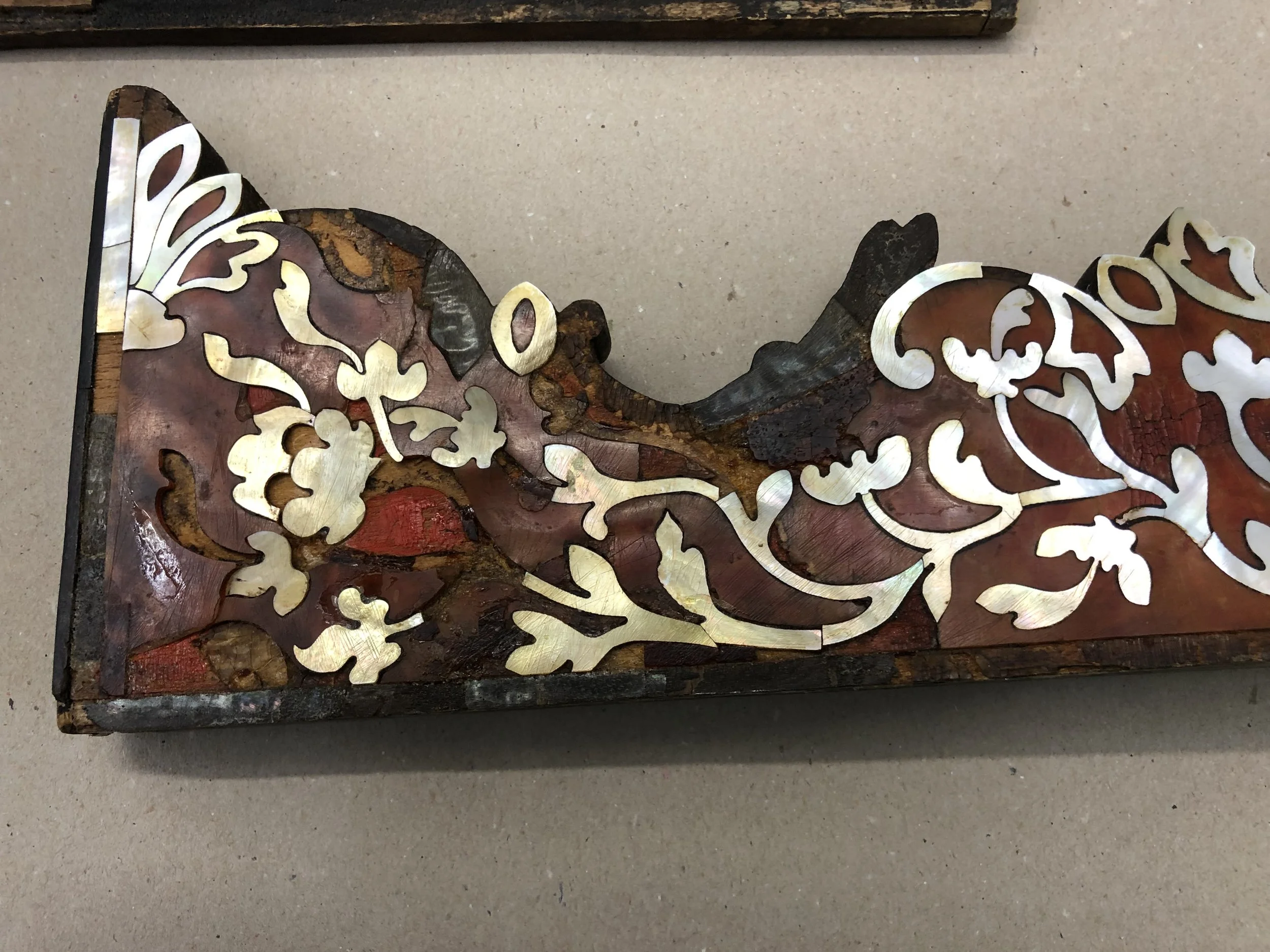 Decorative wooden plaque with intricate inlay design, featuring floral and abstract patterns, placed on a flat surface.