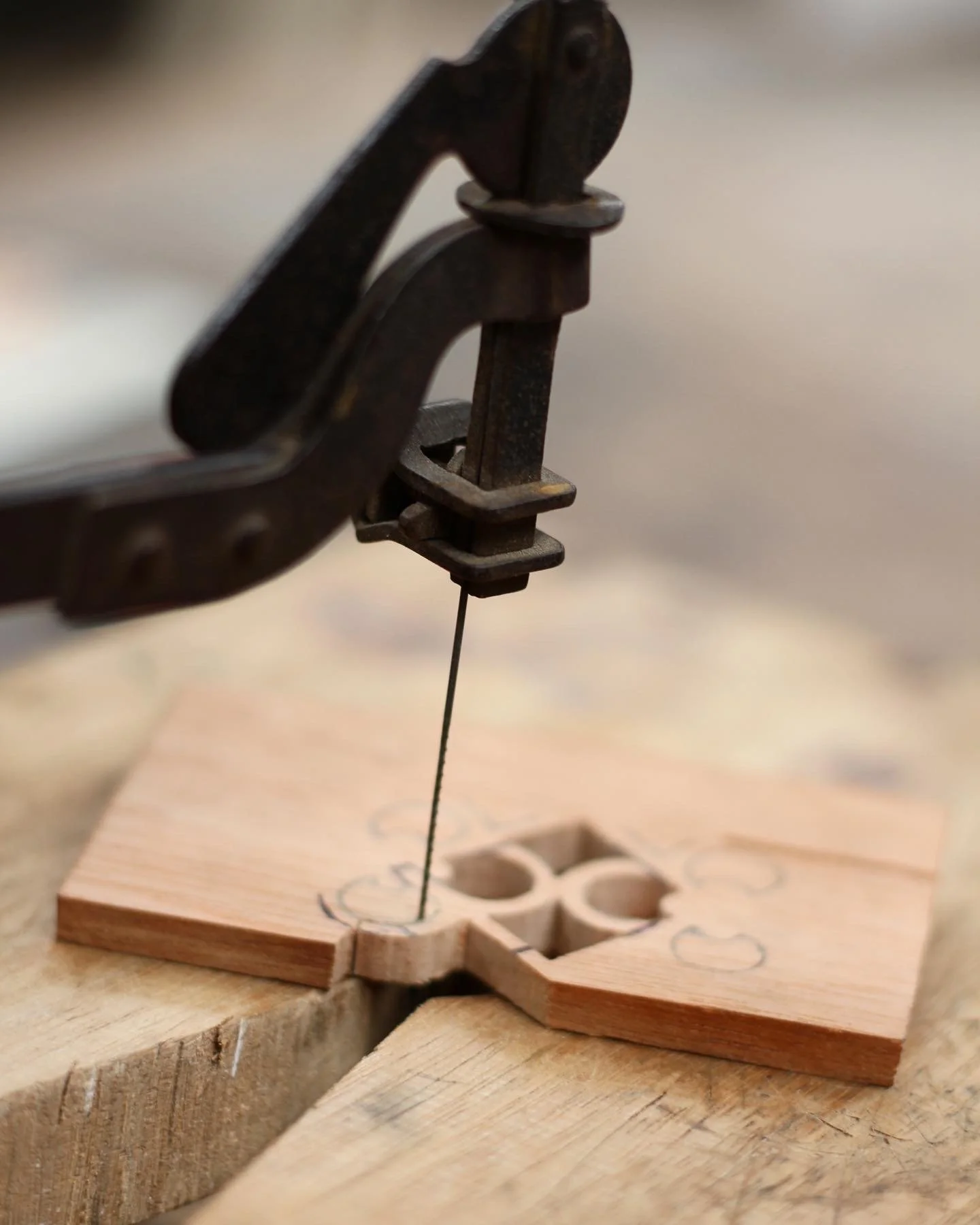 Close-up of a vintage scroll saw cutting a wooden piece with cutout patterns.