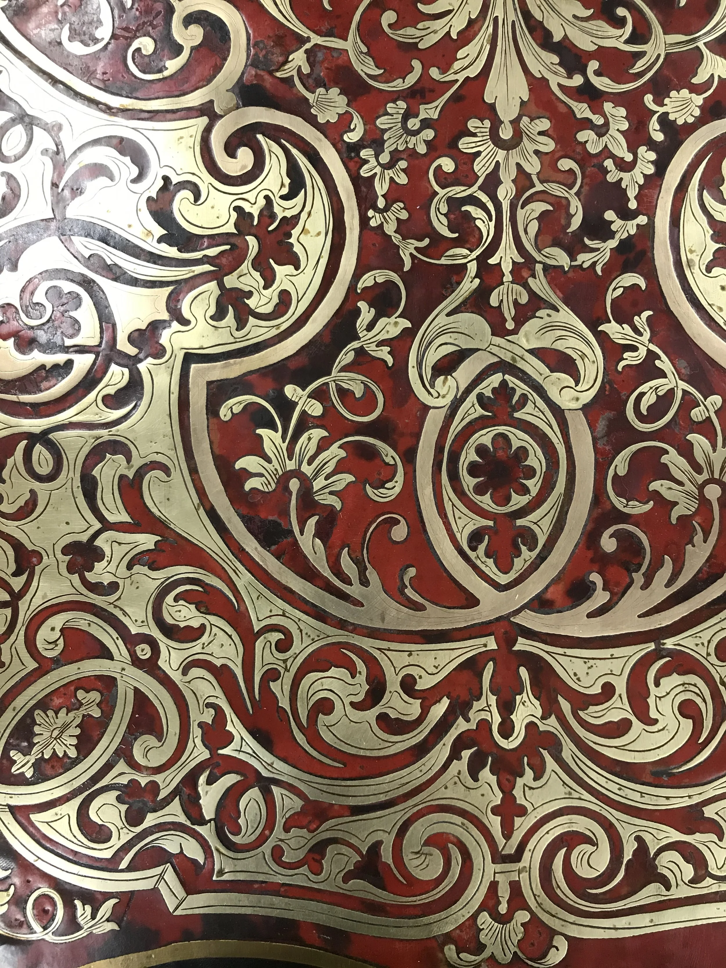 Intricate ornate pattern featuring gold and deep red colors, with floral and scroll designs.