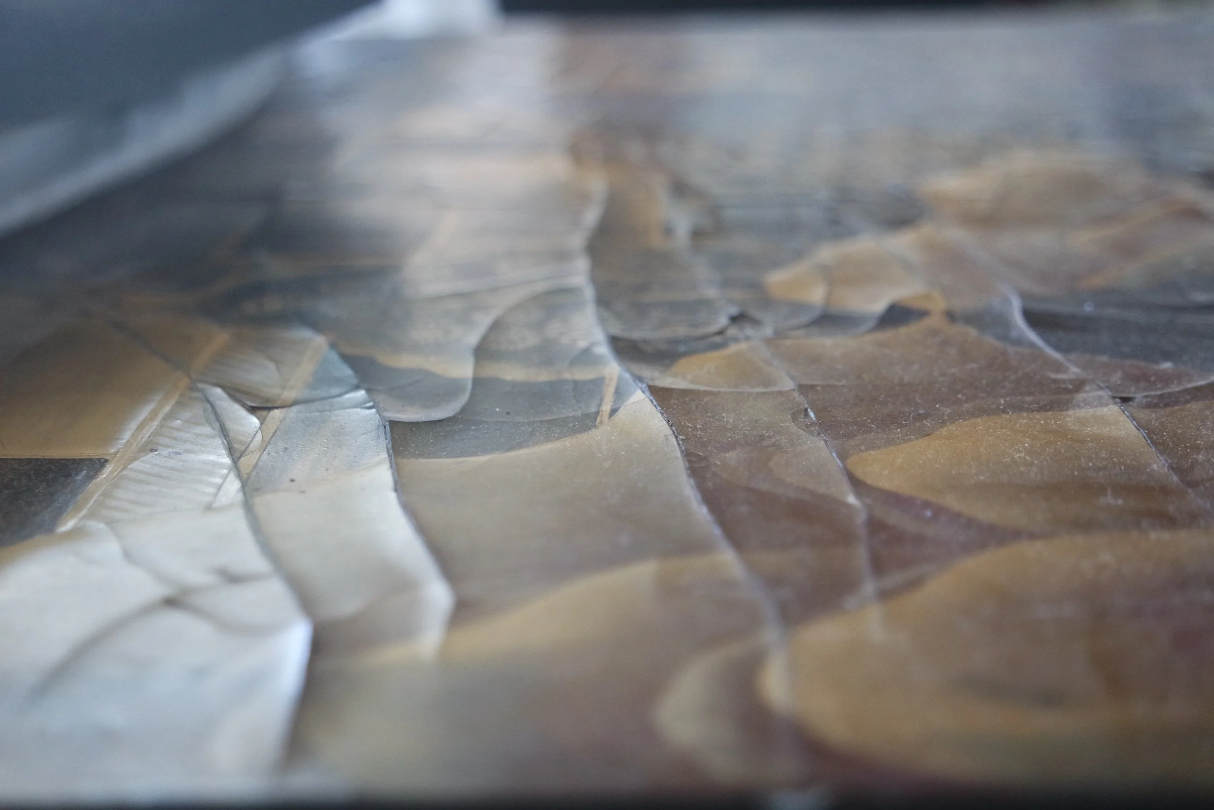 Close-up of an uneven, textured east asian lacquer surface decorated in fine gold patterning.