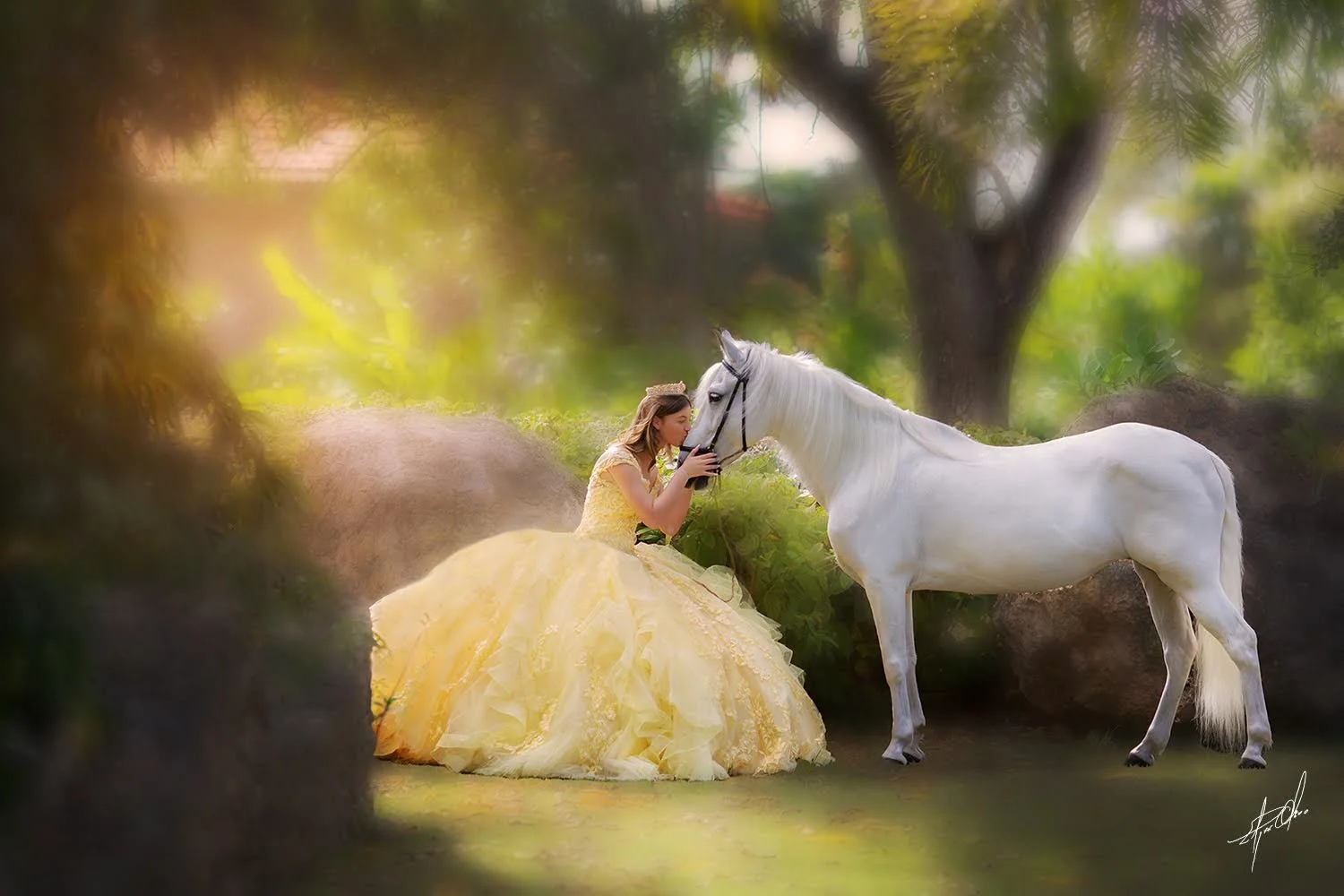 A woman in a yellow dress kissing a white horse in a lush, green outdoor setting.