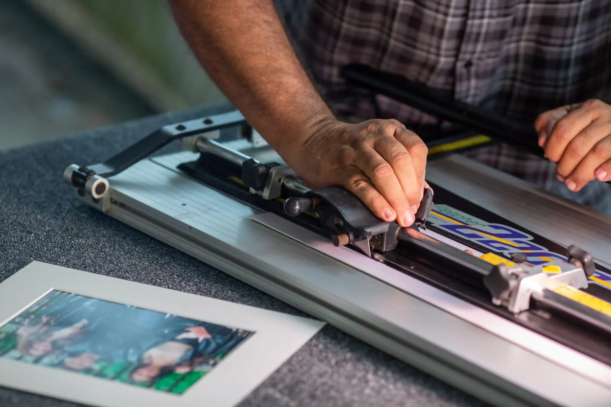 Person operating a paper cutter on a piece of printed material.
