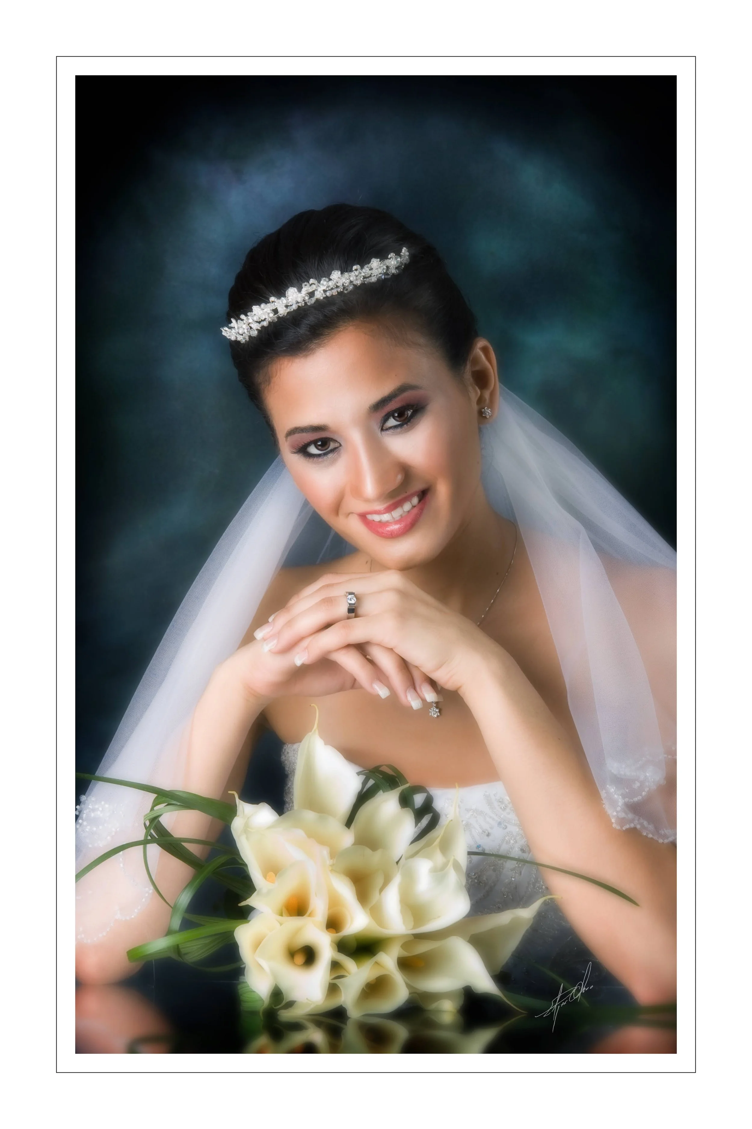 A smiling bride in wedding dress with pearl headband, veil, and jewelry, holding a bouquet of white calla lilies, against a dark, cloudy background.