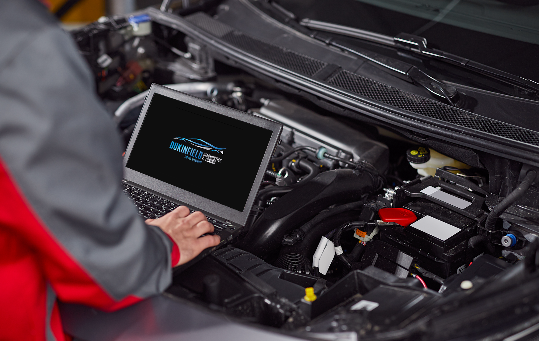 Vehicle diagnostics being carried out on a car engine using specialist laptop software.