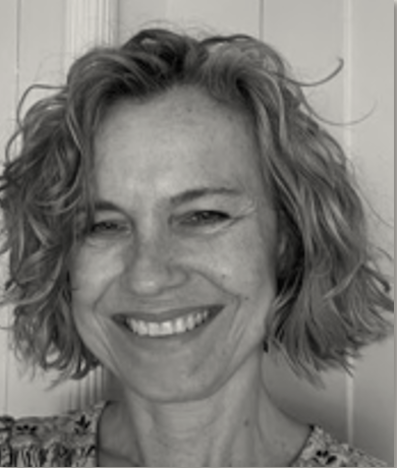 Black and white close-up portrait of a woman with curly hair smiling.