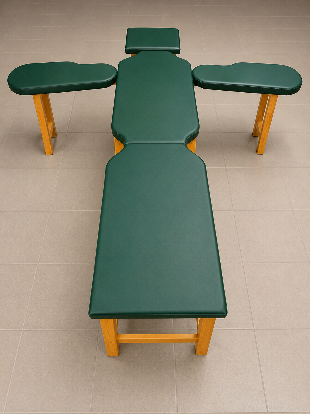 Letto da massaggi con struttura in legno e rivestimento in ecopelle verde, posizionato in una stanza con pavimento in piastrelle beige.