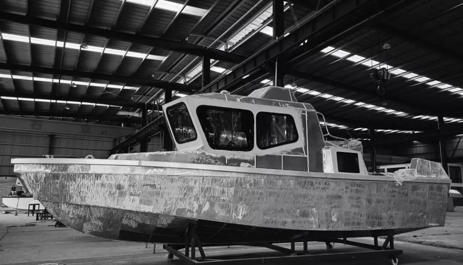 A black and white industrial view of APEX TECH MARINE's (APEXSEA) polar-class marine aluminum hull under construction inside the shipyard,highlighting the heavy-duty structural frames and high-tensile engineering quality.