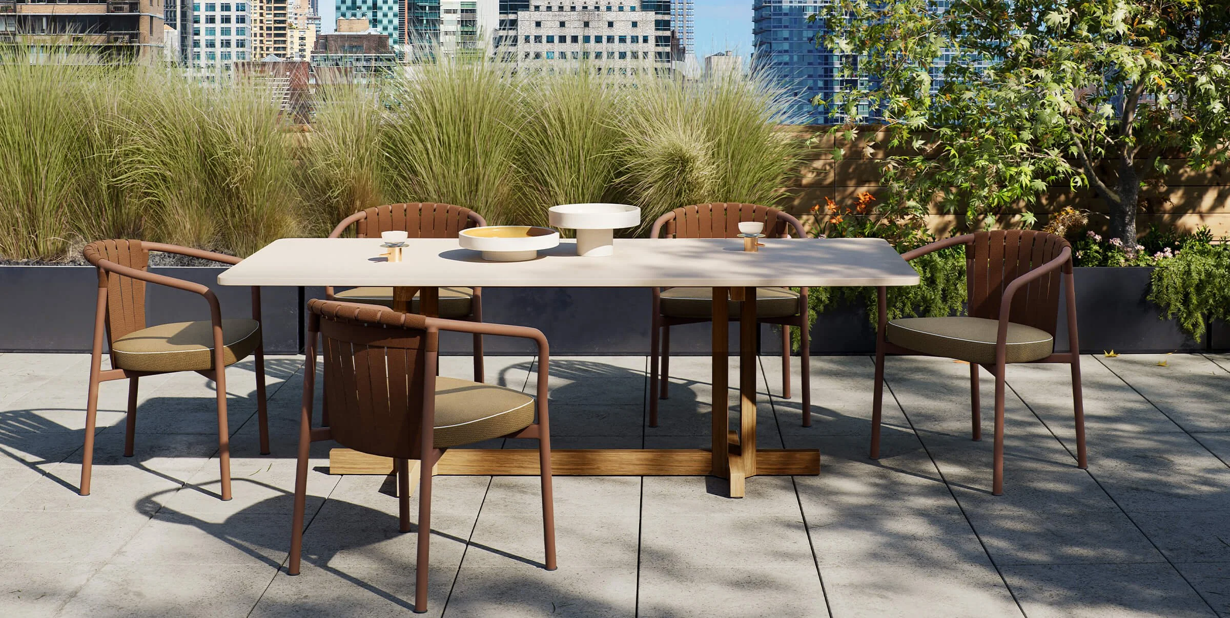 Outdoor patio with a white table and six brown chairs, set against a backdrop of tall grasses, trees, and city buildings.