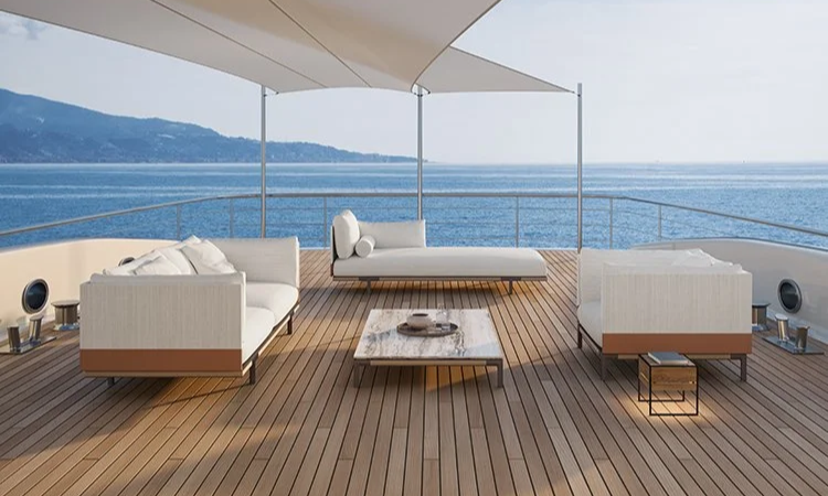 Luxury yacht deck with white outdoor furniture, a coffee table, and ocean view with distant hills.