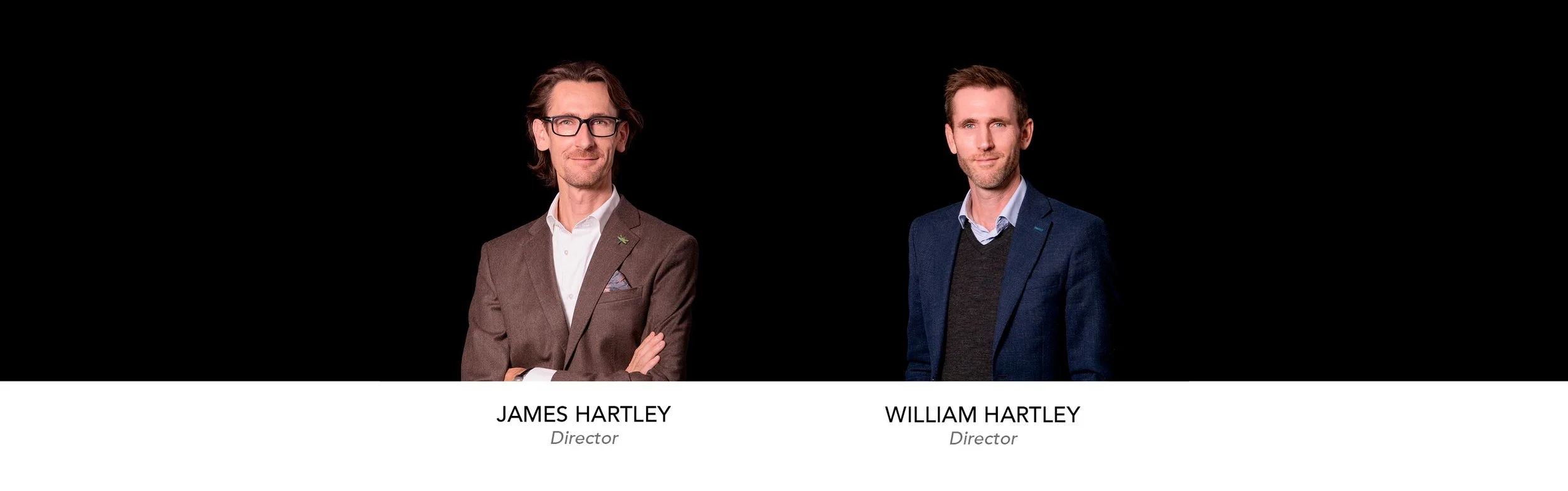 Photograph of two men dressed in suits standing against a black background with their names and titles displayed below: James Hartley, Director and William Hartley, Director.